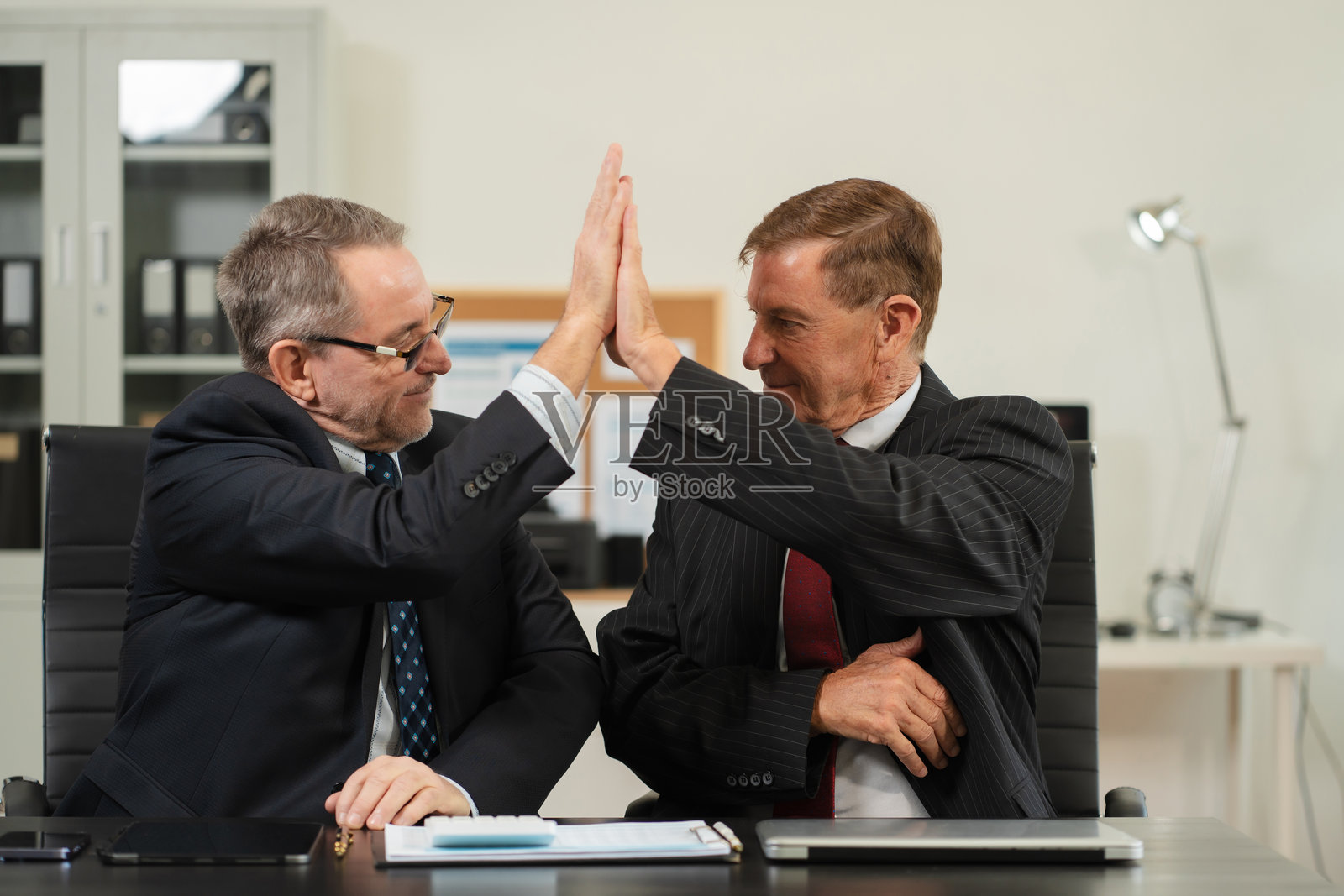 快乐的创意商务人士充满动力，互相击掌庆祝成功的交易。照片摄影图片