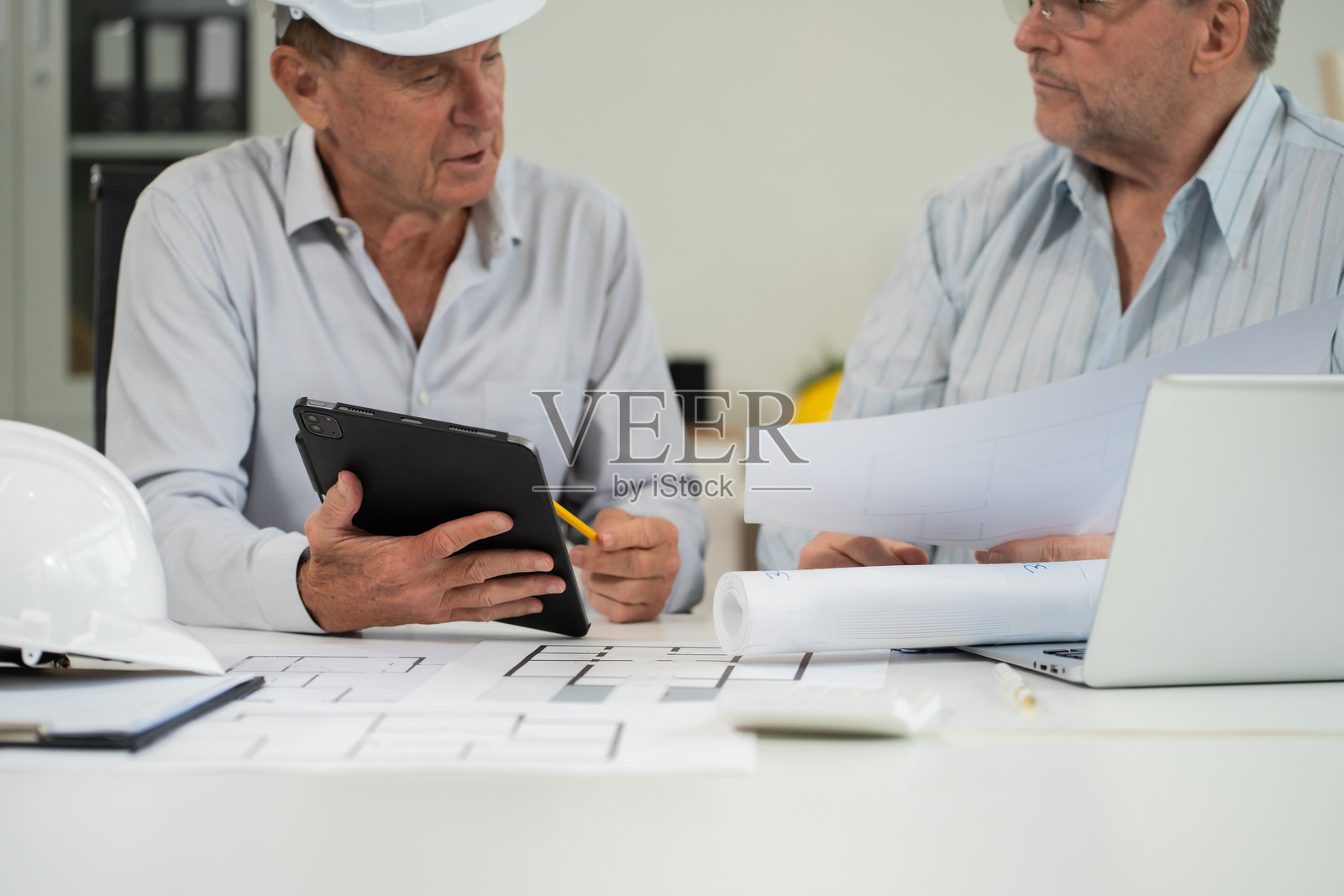 白人建筑师在桌子上使用绘图工具绘制商业建筑项目的纸质计划。照片摄影图片