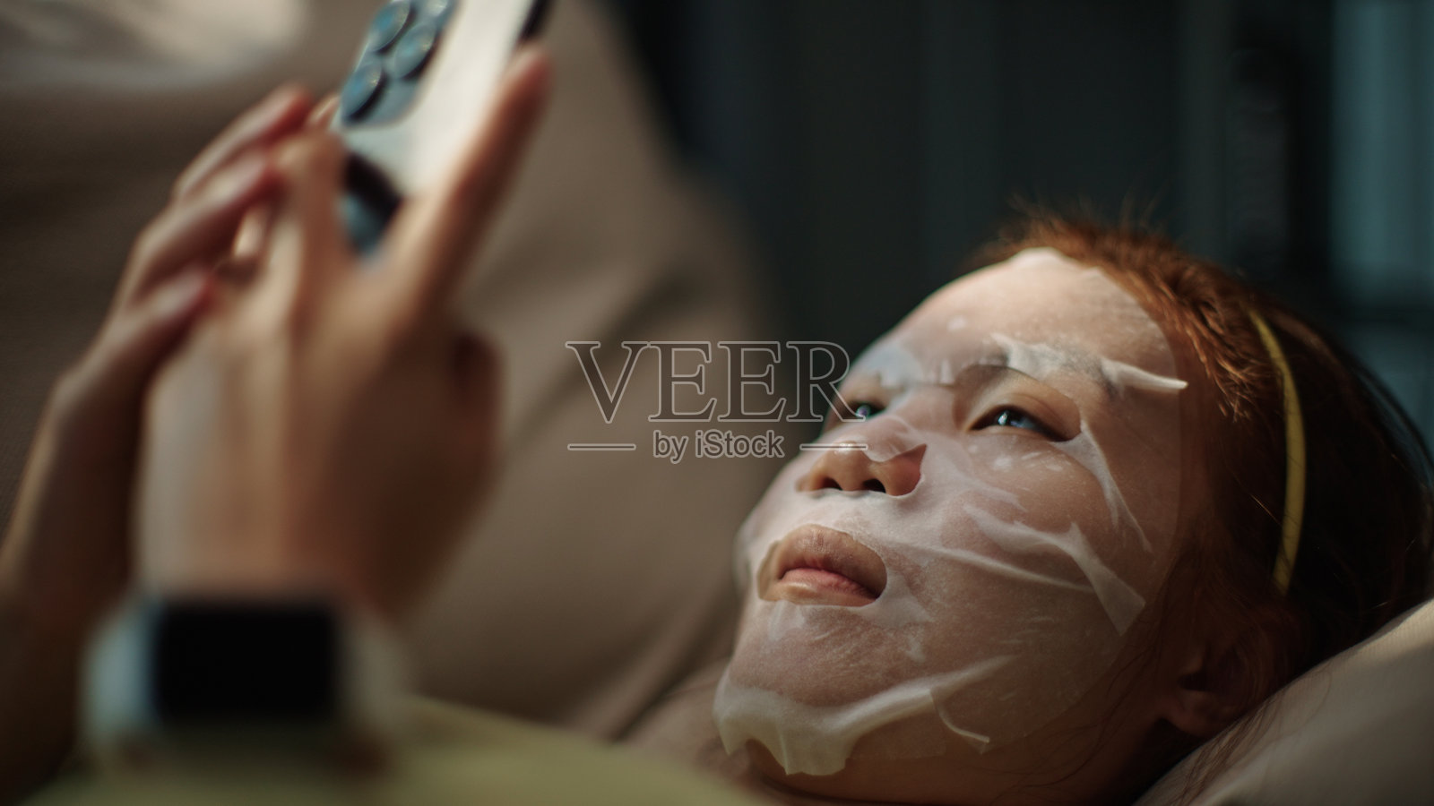 戴着面罩的青少年使用智能手机。照片摄影图片