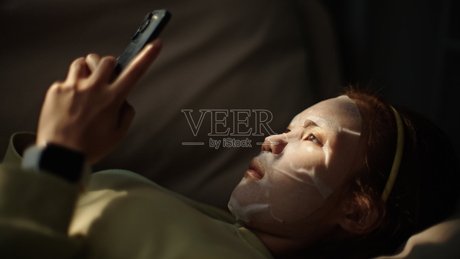 戴着面罩的青少年使用智能手机。照片摄影图片