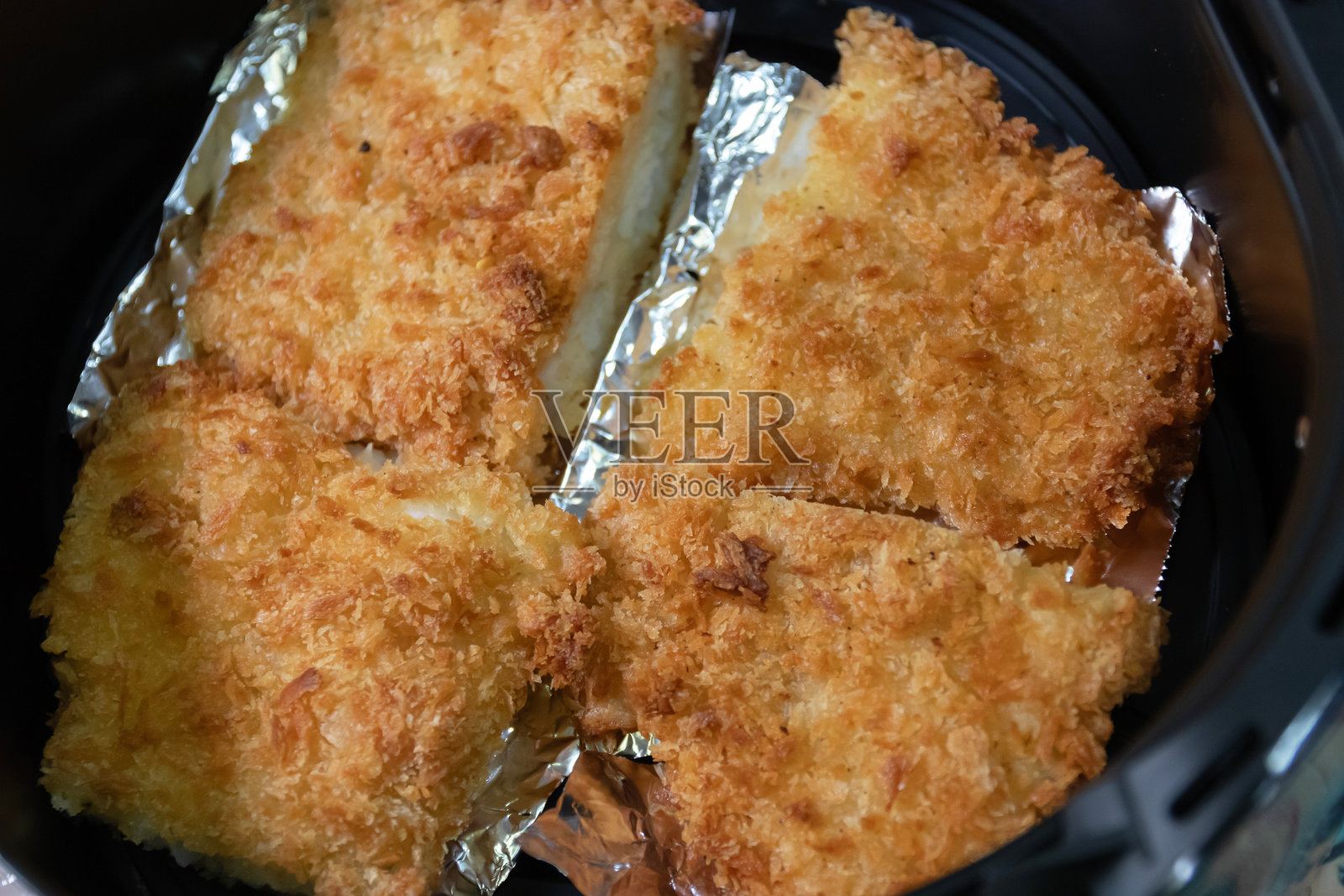 空气炸锅中酥脆的炸鱼片，展现金黄色的外壳和美味的口感，完美适合健康餐。照片摄影图片