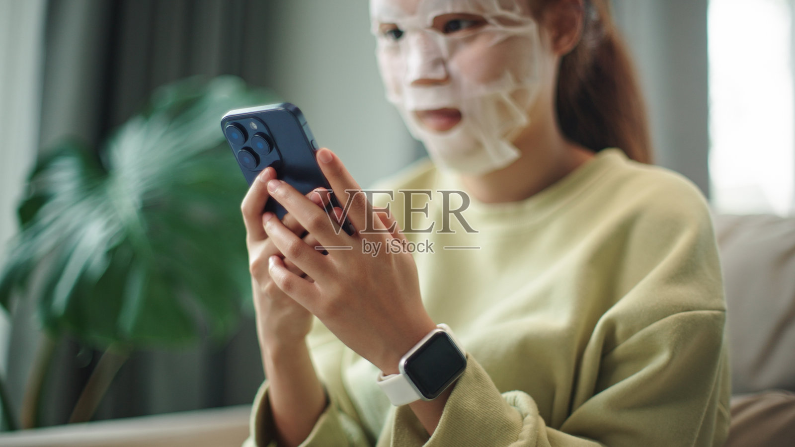 戴着面膜的青少年使用智能手机。照片摄影图片