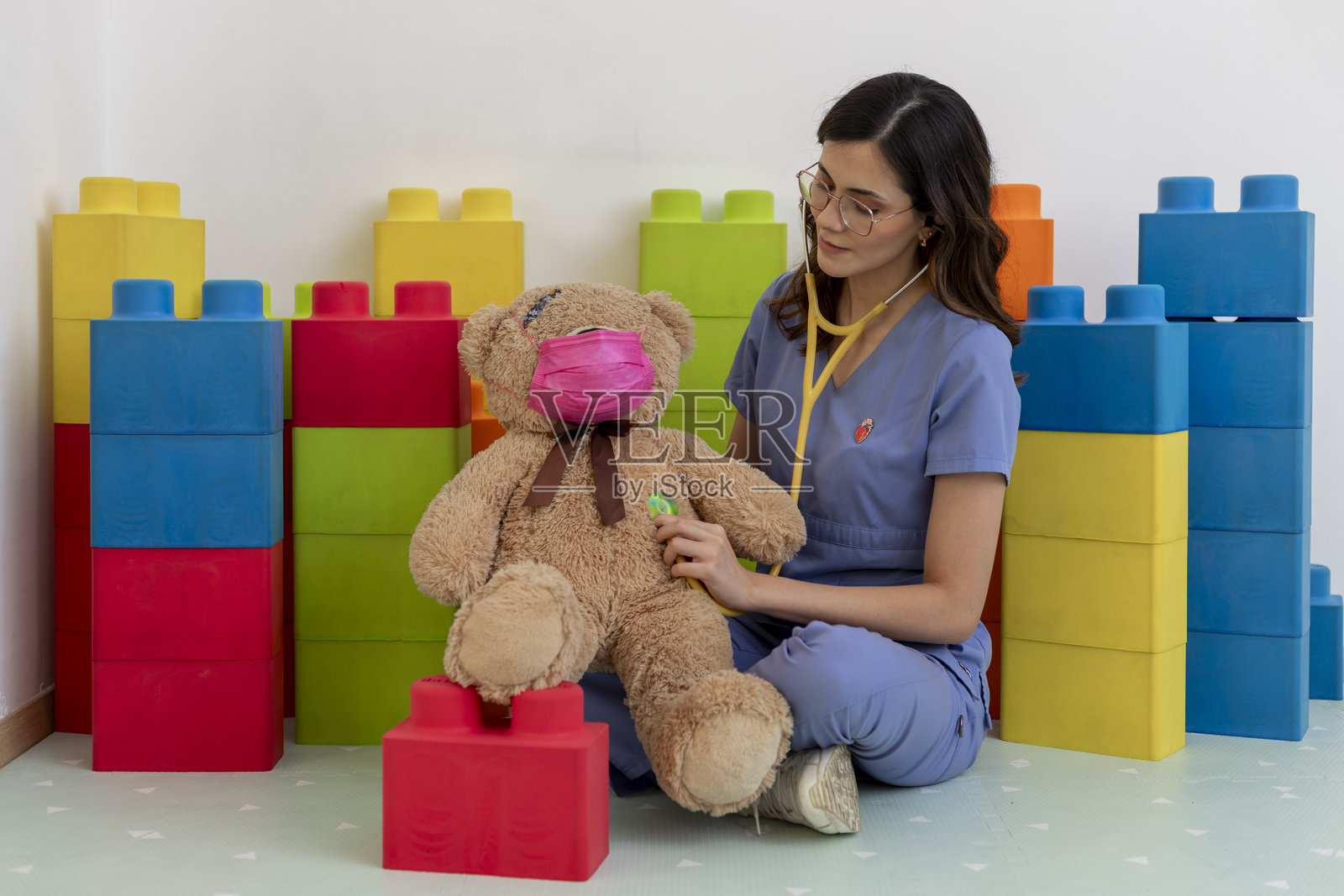 儿科医生使用听诊器检查戴着防护口罩的泰迪熊照片摄影图片