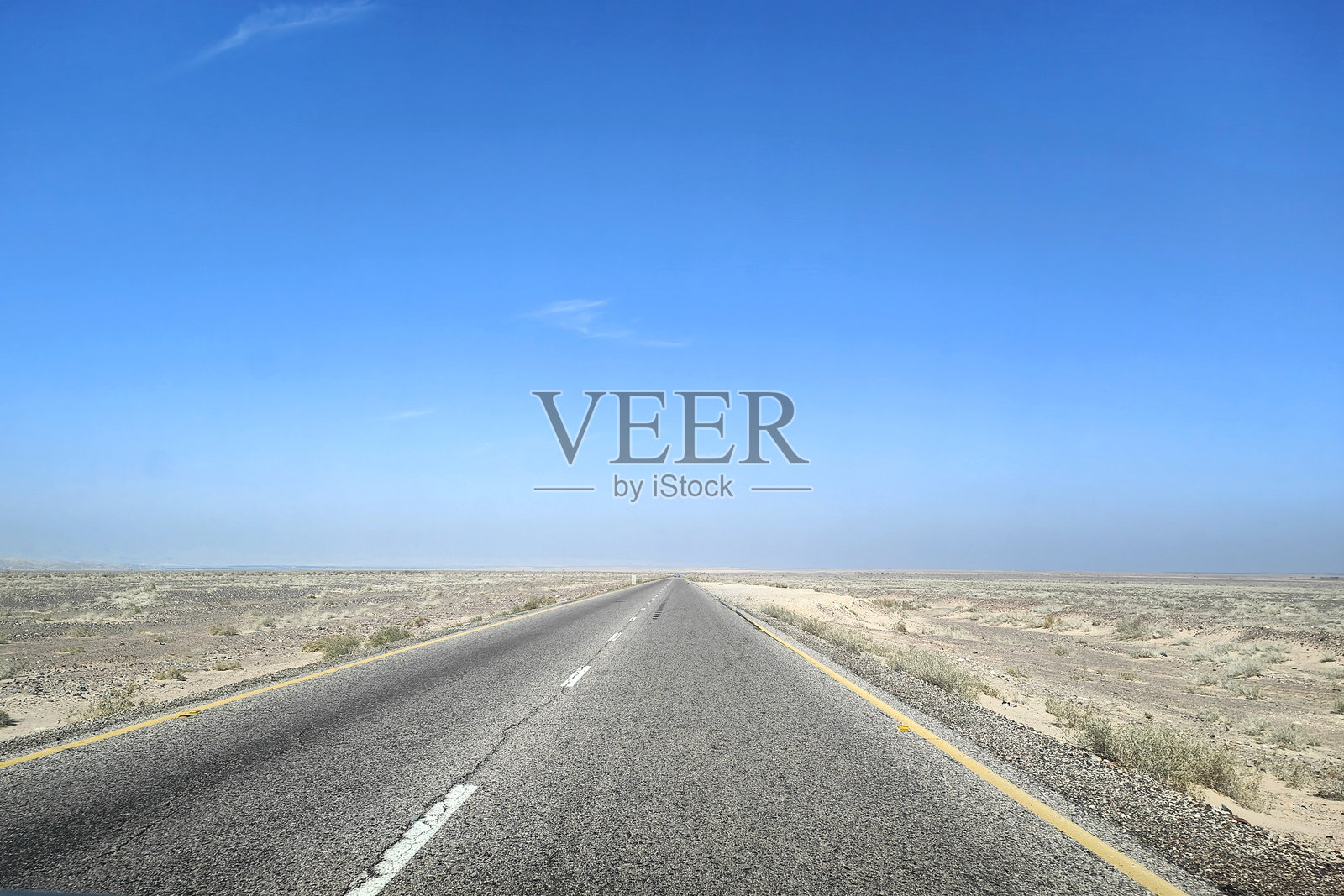 无尽的沙漠公路在晴朗的蓝天下照片摄影图片