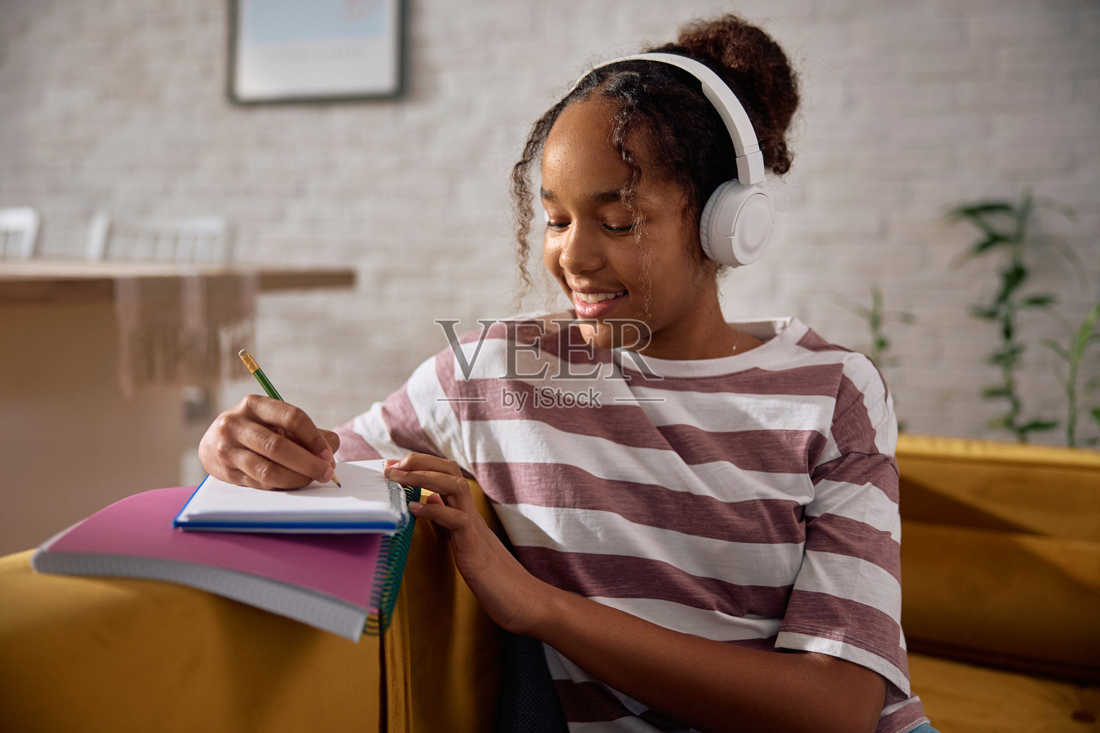 快乐的黑人少女在家学习时做笔记。照片摄影图片