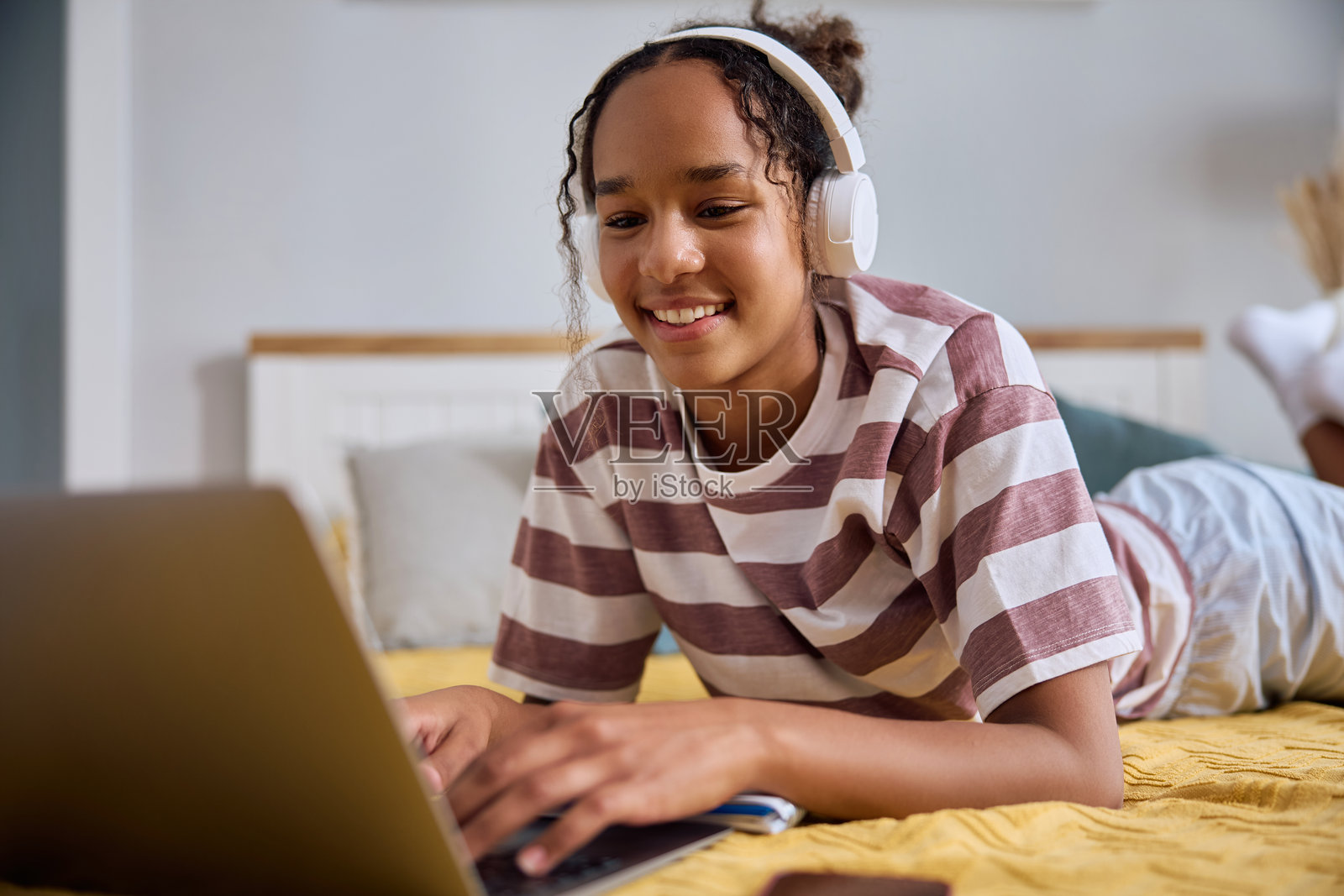 快乐的非裔美国少女在家中使用笔记本电脑。照片摄影图片
