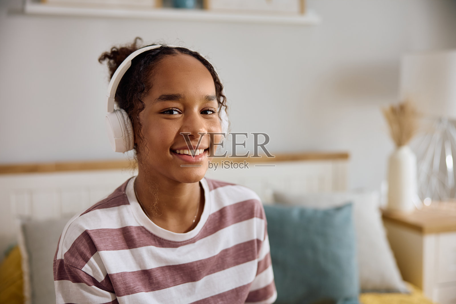 快乐的黑人少女戴着耳机微笑着看向镜头。照片摄影图片