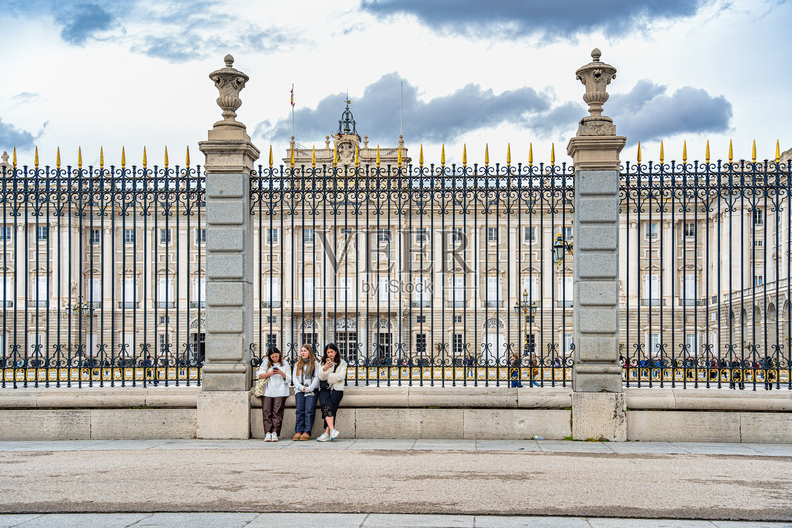 三位年轻女性站在标志性的马德里皇家宫殿前照片摄影图片