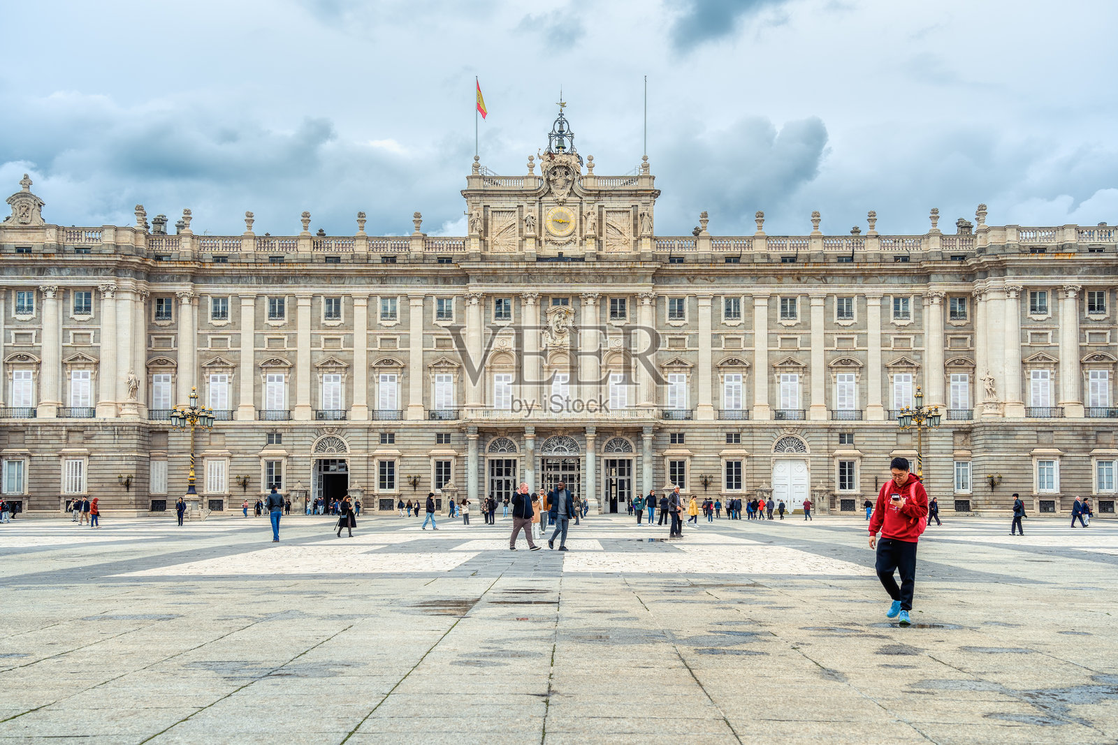 马德里皇家宫殿下壮观的新古典主义建筑与戏剧性的多云天空。照片摄影图片