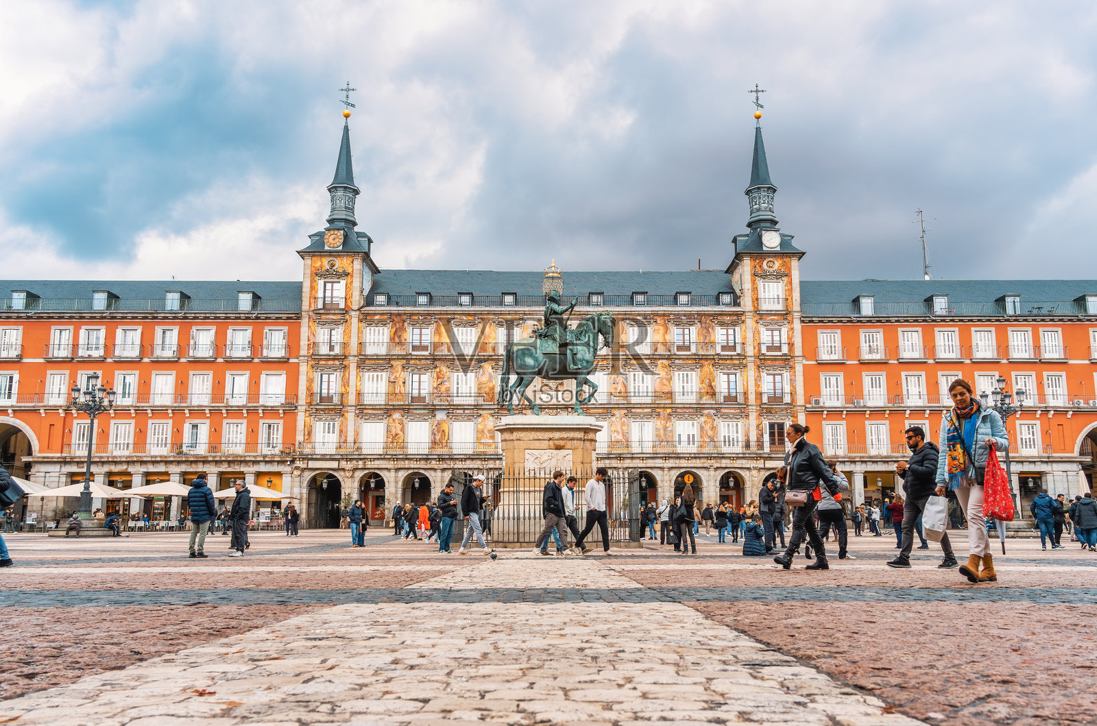 人们在马德里的马约尔广场（Plaza Mayor）悠闲地漫步，站在菲利普三世国王雕像（Estatua de Felipe III）前。照片摄影图片