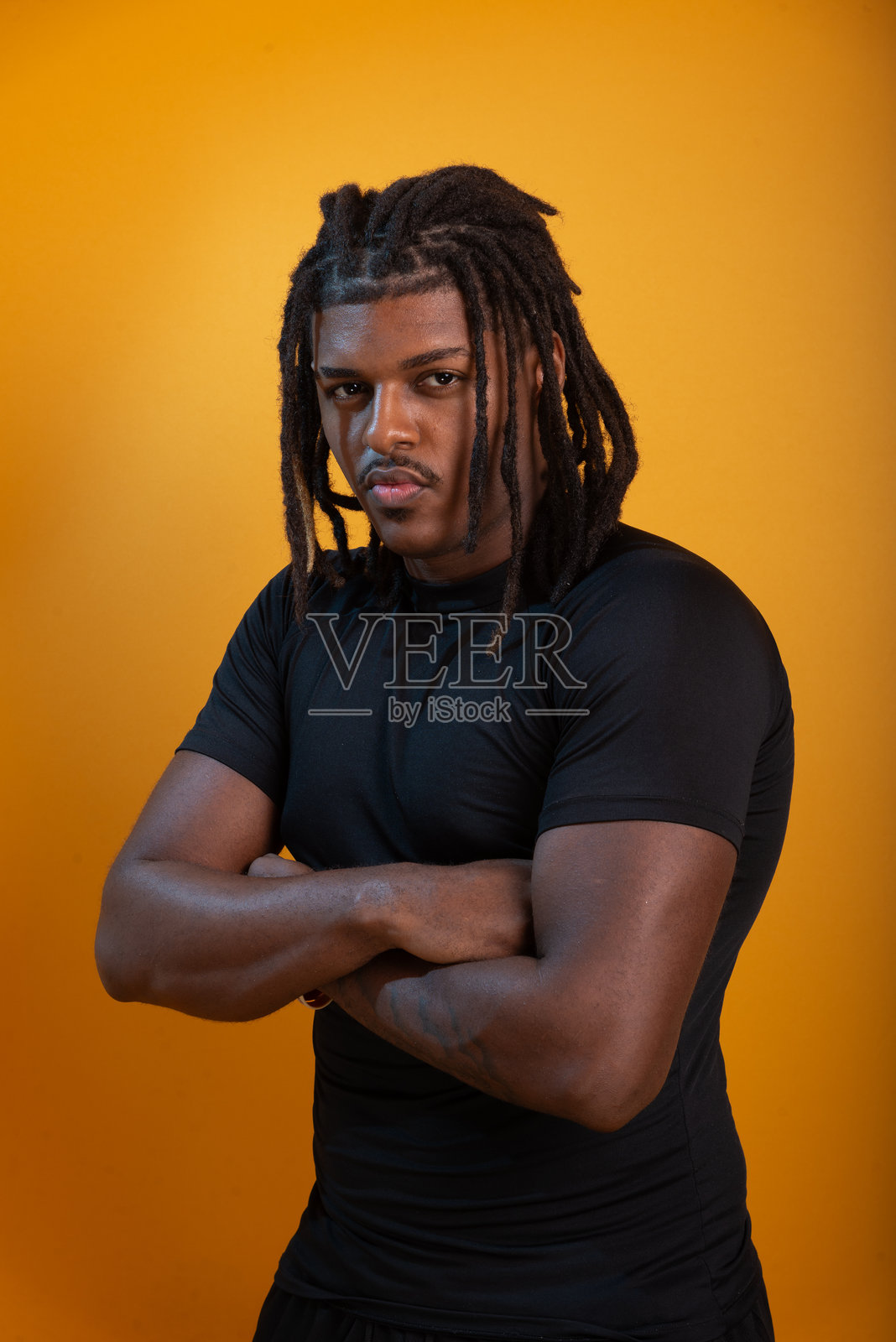 身穿黑色服装的英俊年轻男子在橙色背景前摆姿势拍摄肖像。照片摄影图片