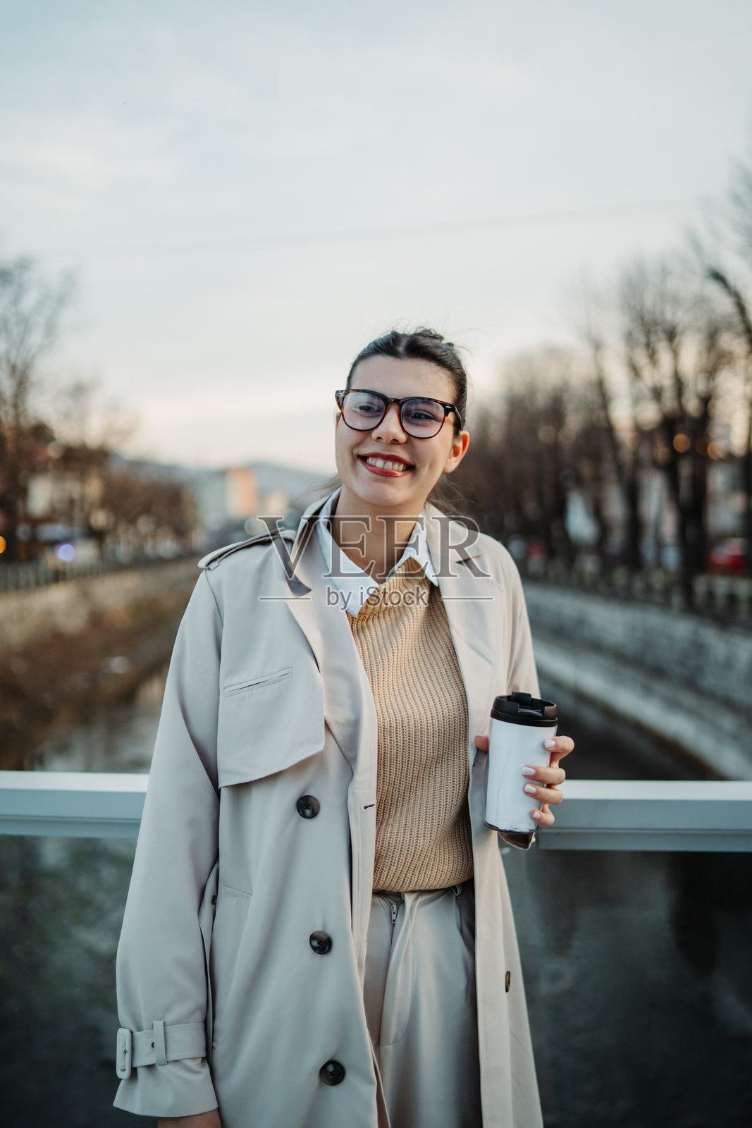 年轻的白人女性下班回家，喝着咖啡并使用手机。照片摄影图片