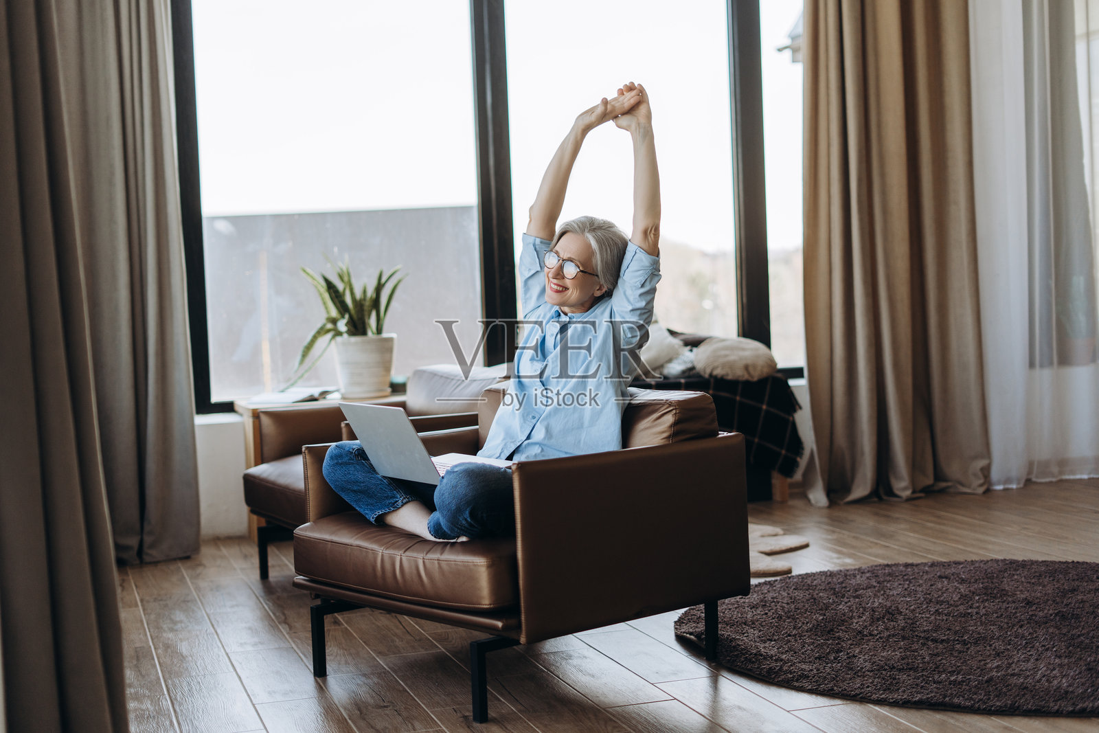 在家办公的老年女性伸展身体照片摄影图片