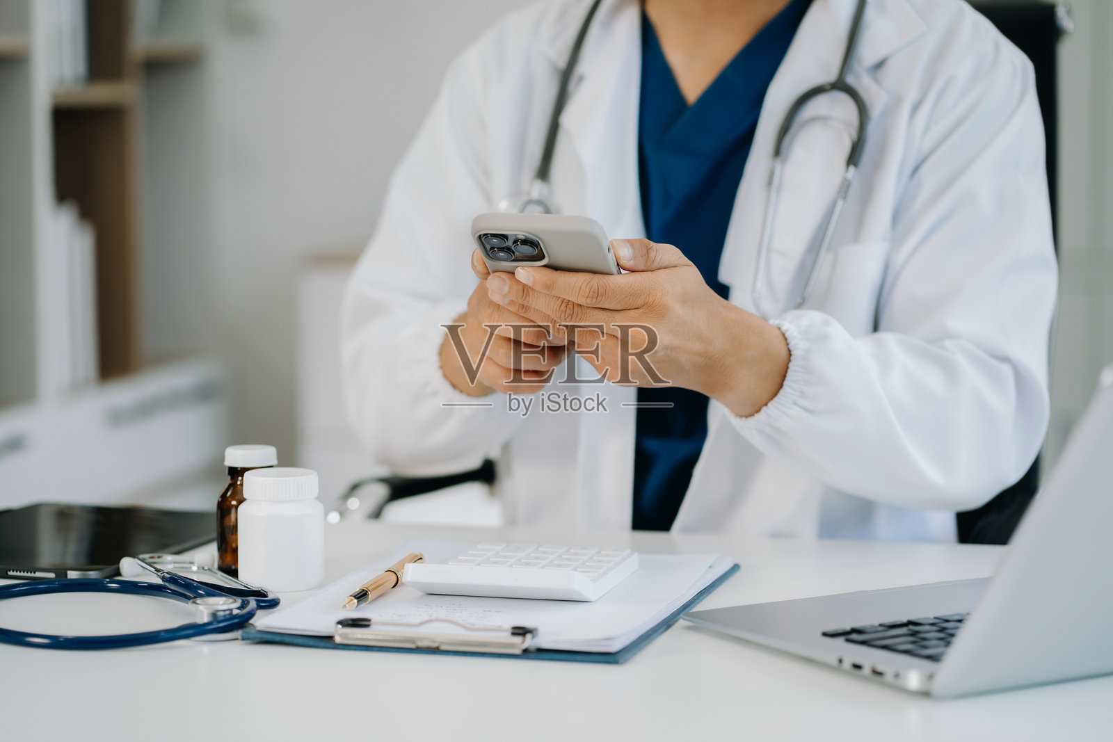 男医生在办公室使用手机浏览社交媒体。照片摄影图片