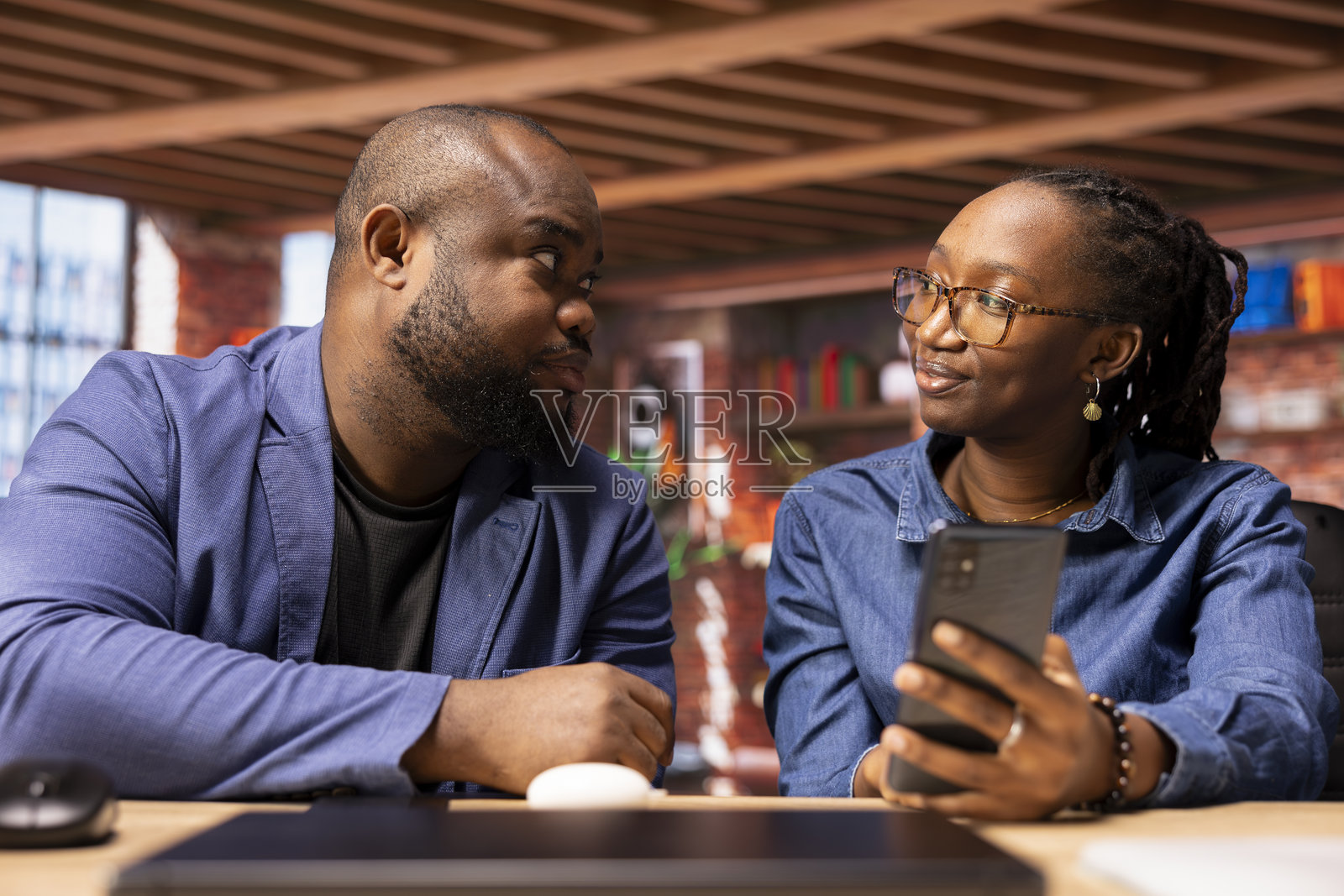 一对非裔美国自由职业者夫妇在回复邮件和查看社交媒体。照片摄影图片