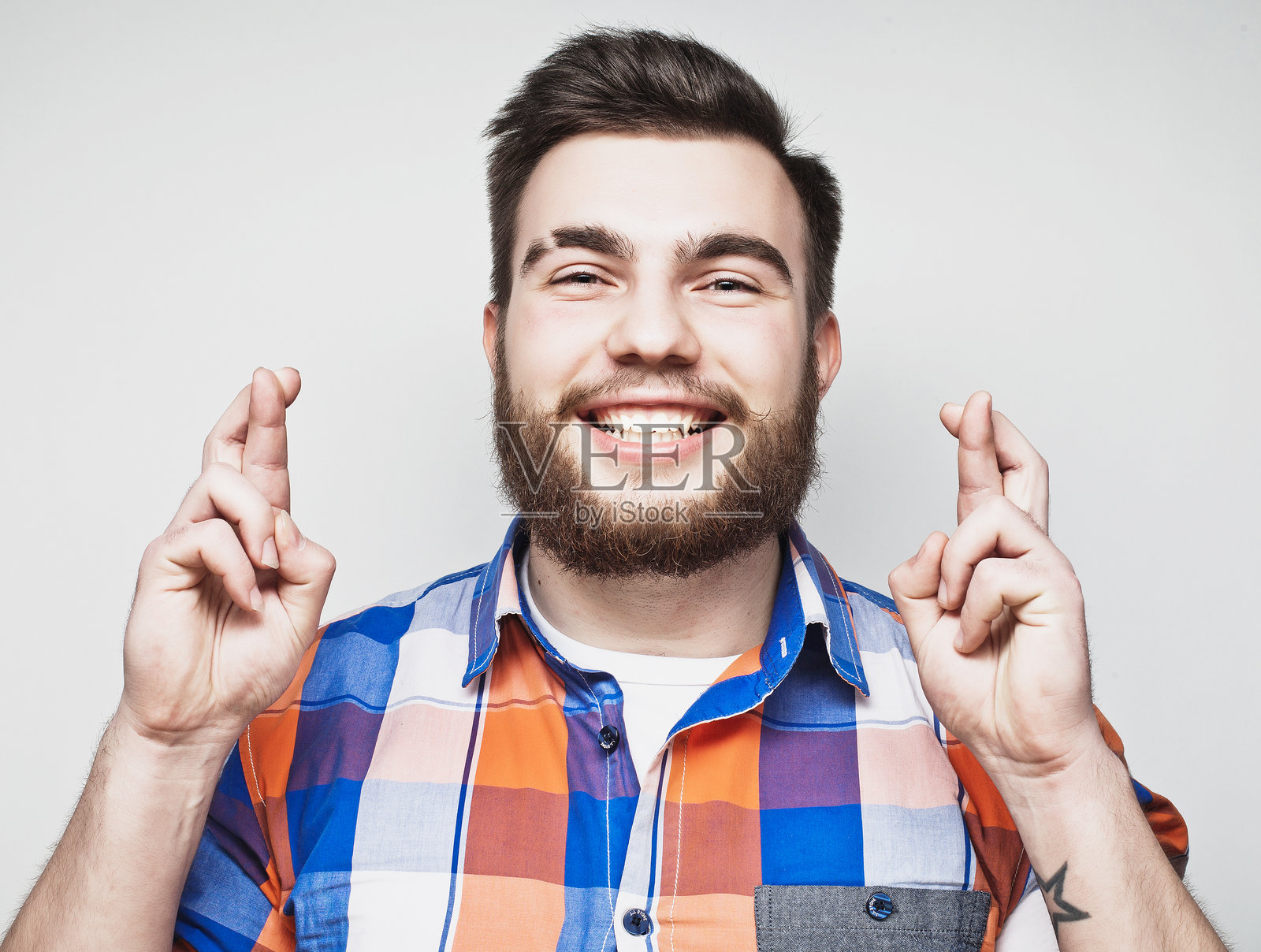 年轻的胡须男士穿着衬衫，手指保持着某种姿势照片摄影图片