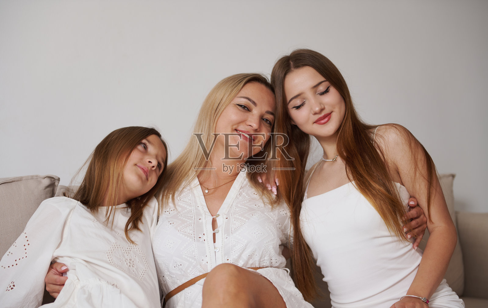 慈爱的母亲与她的两个女儿在沙发上共享美好时光照片摄影图片