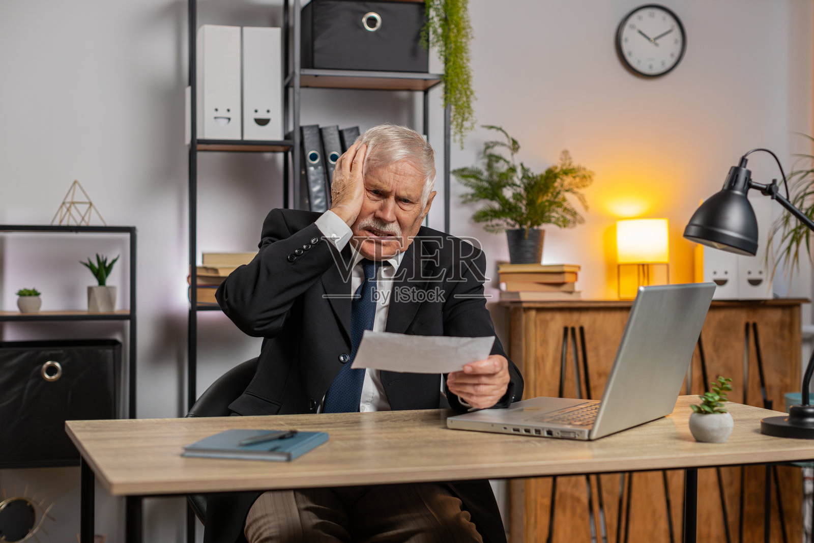 震惊的老年商人在办公桌上打开信封，阅读信中坏消息，感到沮丧。照片摄影图片