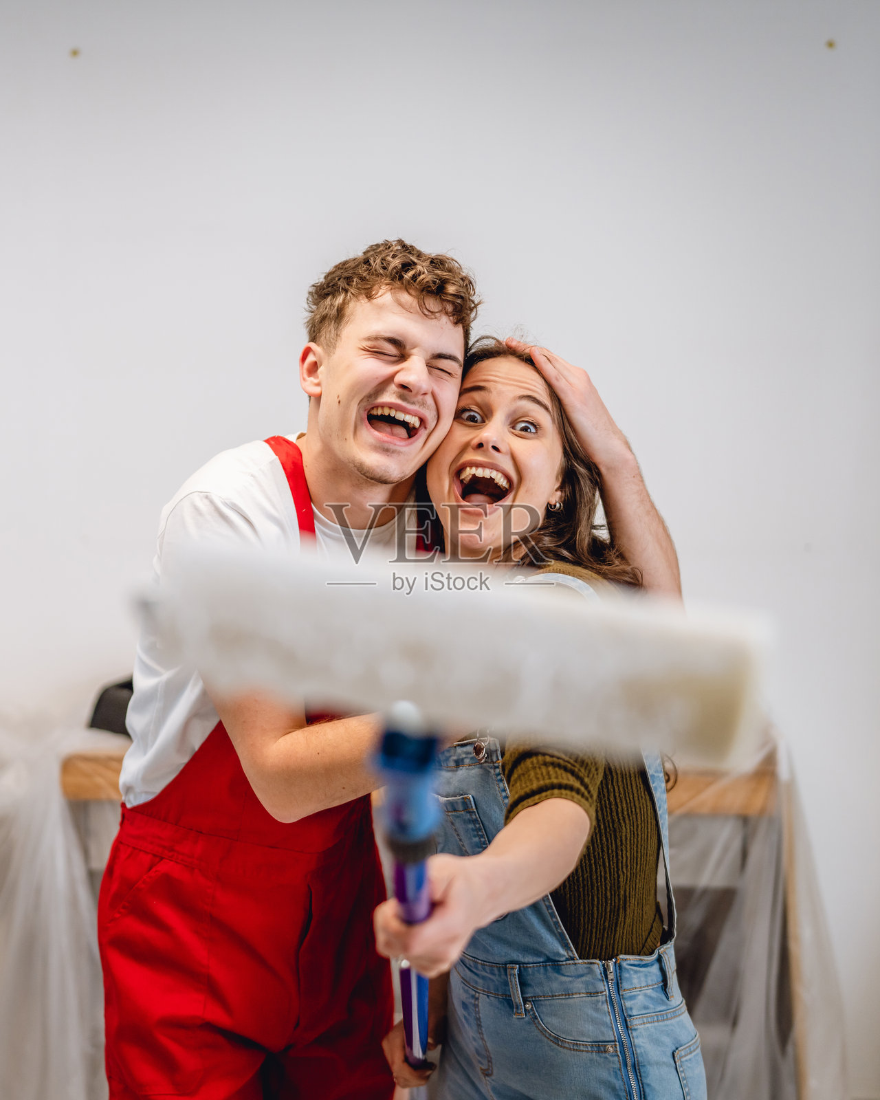 男朋友和女朋友站在一起，手持油漆滚筒的肖像照片摄影图片