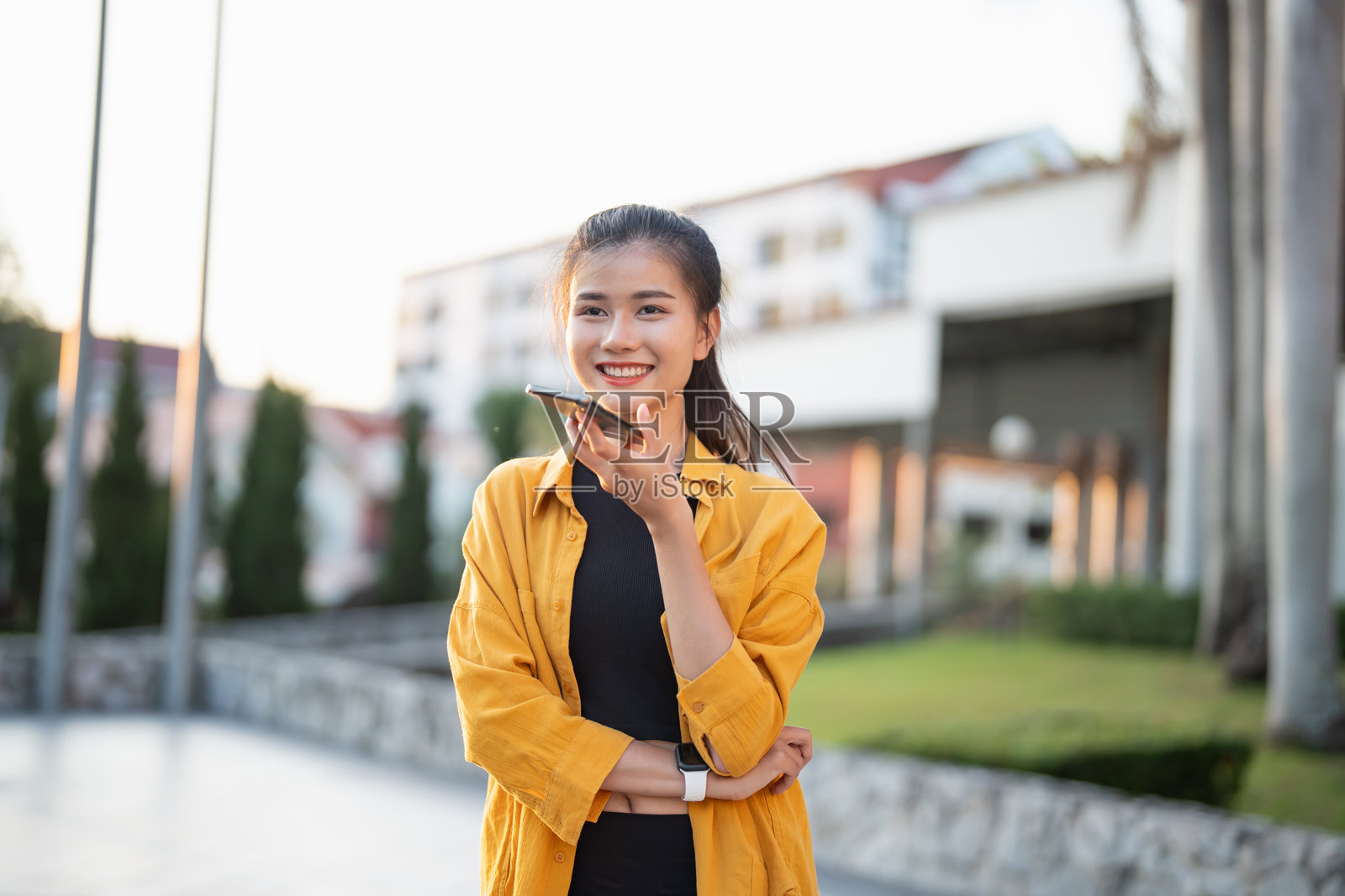微笑的年轻亚洲女性在城市户外使用智能手机查看应用程序照片摄影图片