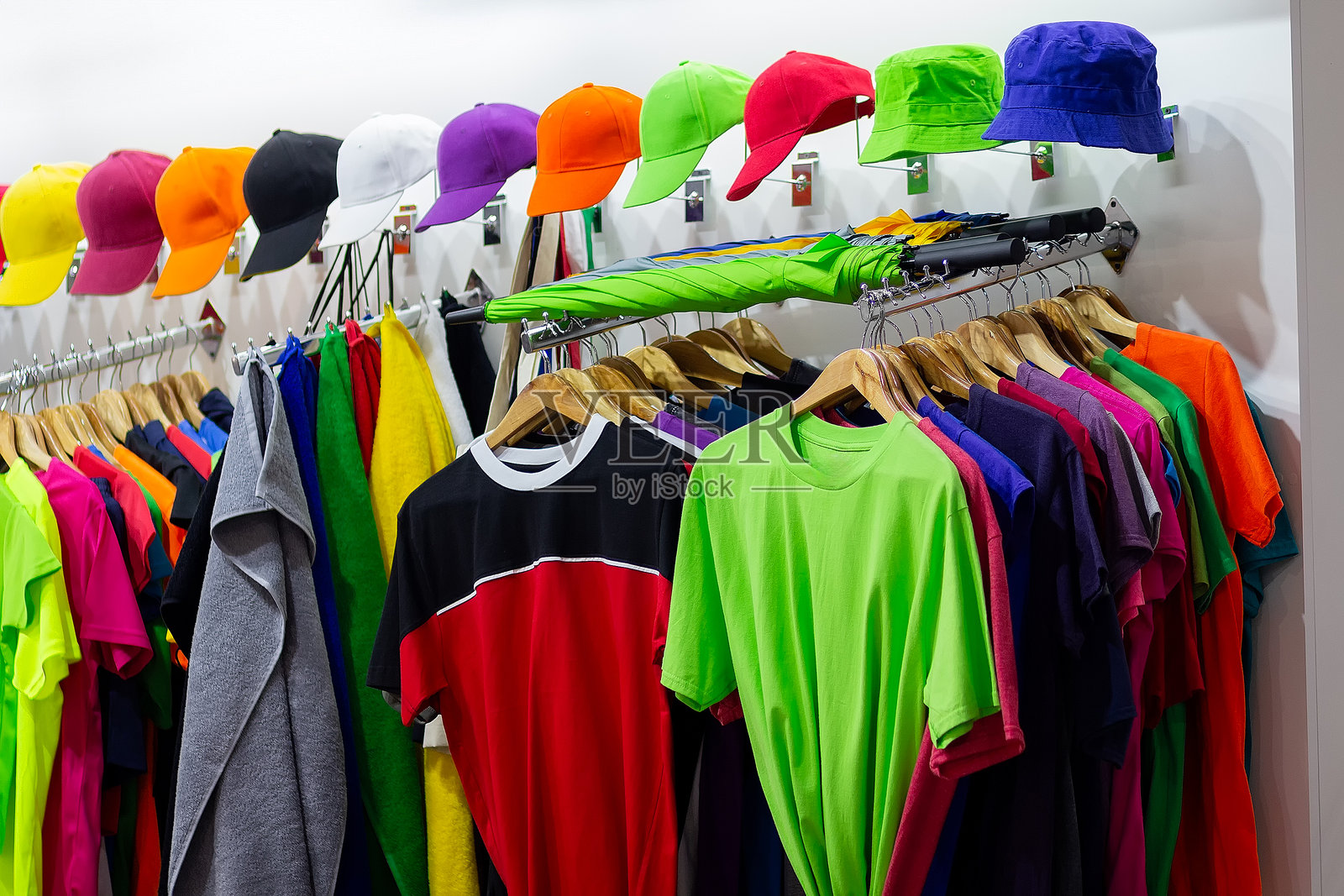 运动商店窗户上的多彩T恤和棒球帽照片摄影图片