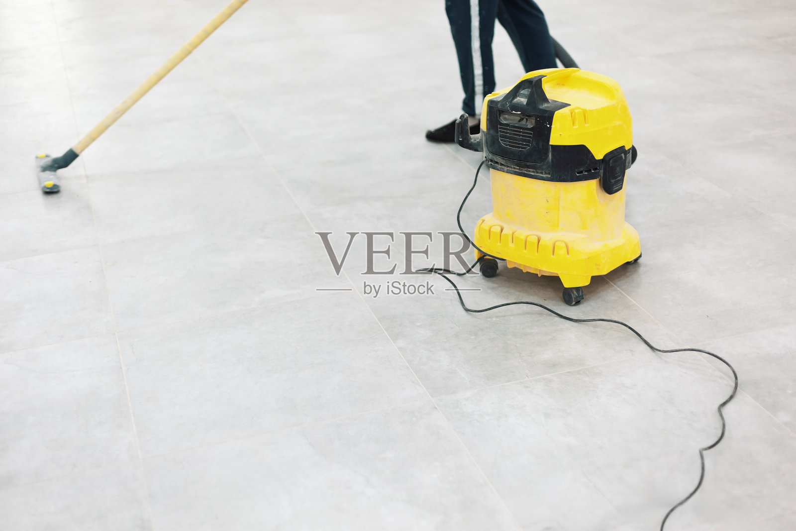 清洁服务人员正在清扫和吸尘一块大型灰色瓷砖地板照片摄影图片