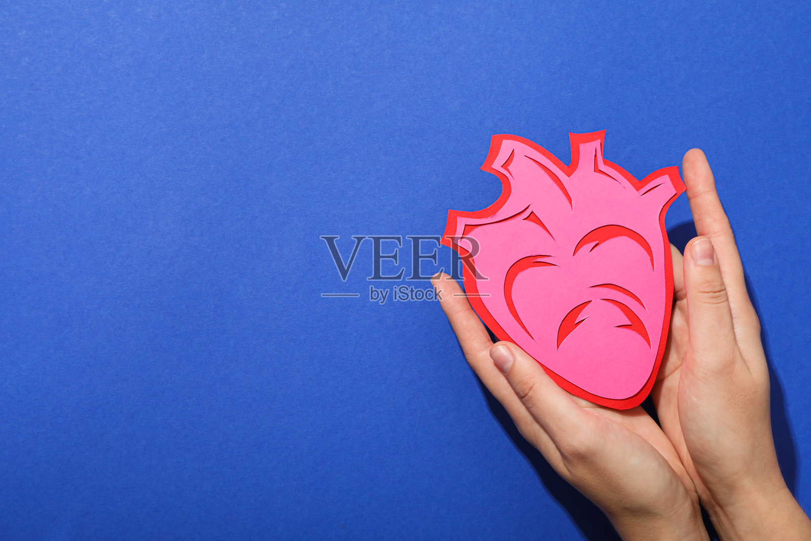 蓝色背景上的心脏，心血管疾病治疗的概念。照片摄影图片