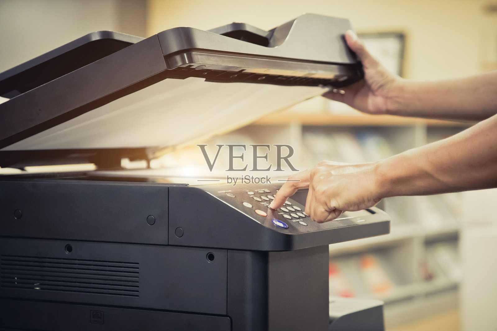 复印机，办公人员的手特写按下面板上的复印按钮，以使用复印机或复印设备进行文档扫描和打印纸张的复印。照片摄影图片
