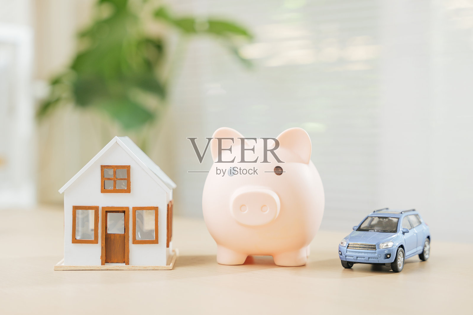 储蓄罐与房屋和蓝色汽车模型象征着为梦想家园和汽车存钱。强调房地产投资、资产积累和财务管理。照片摄影图片