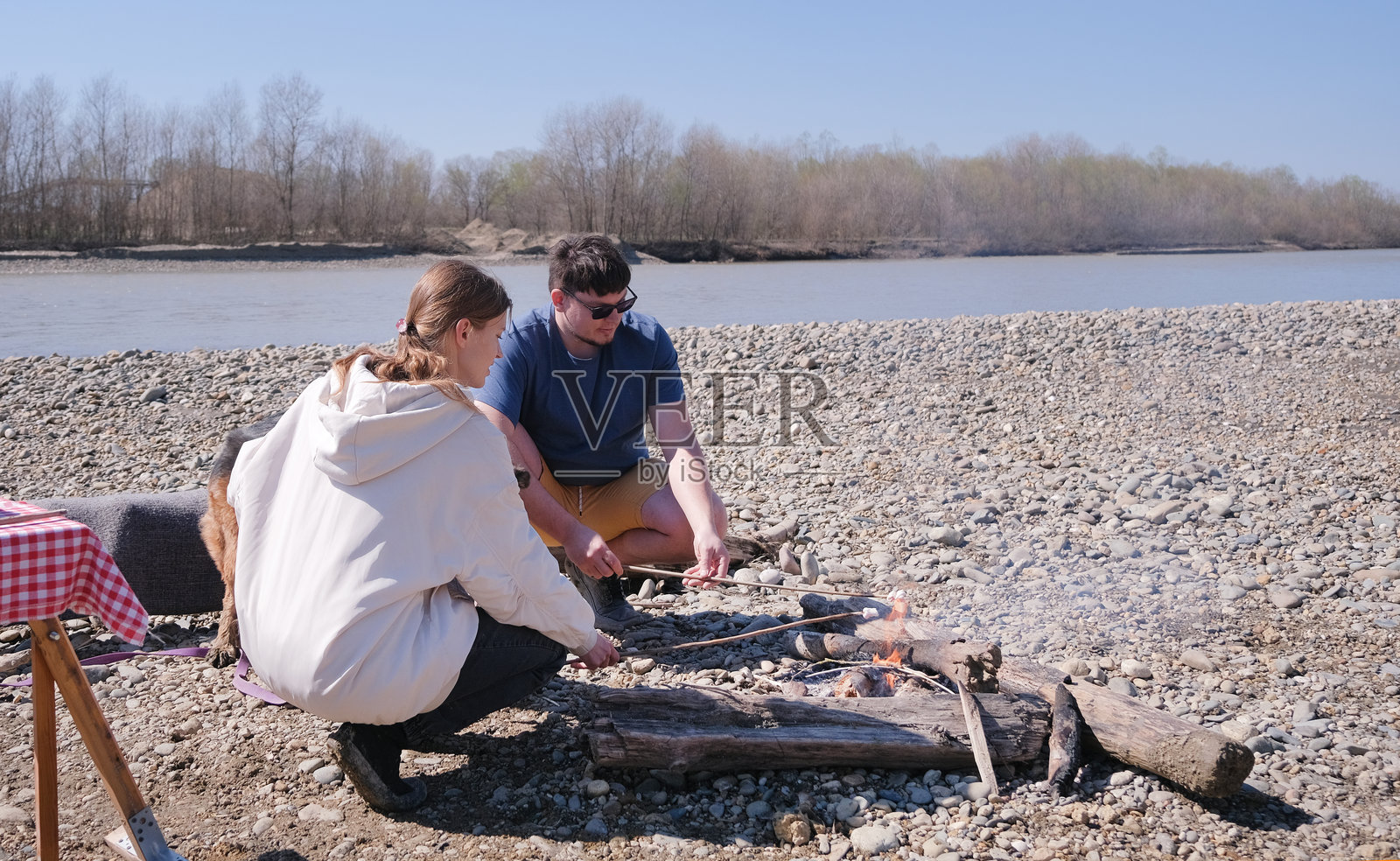 一家人在河边野餐，带着他们的狗。照片摄影图片