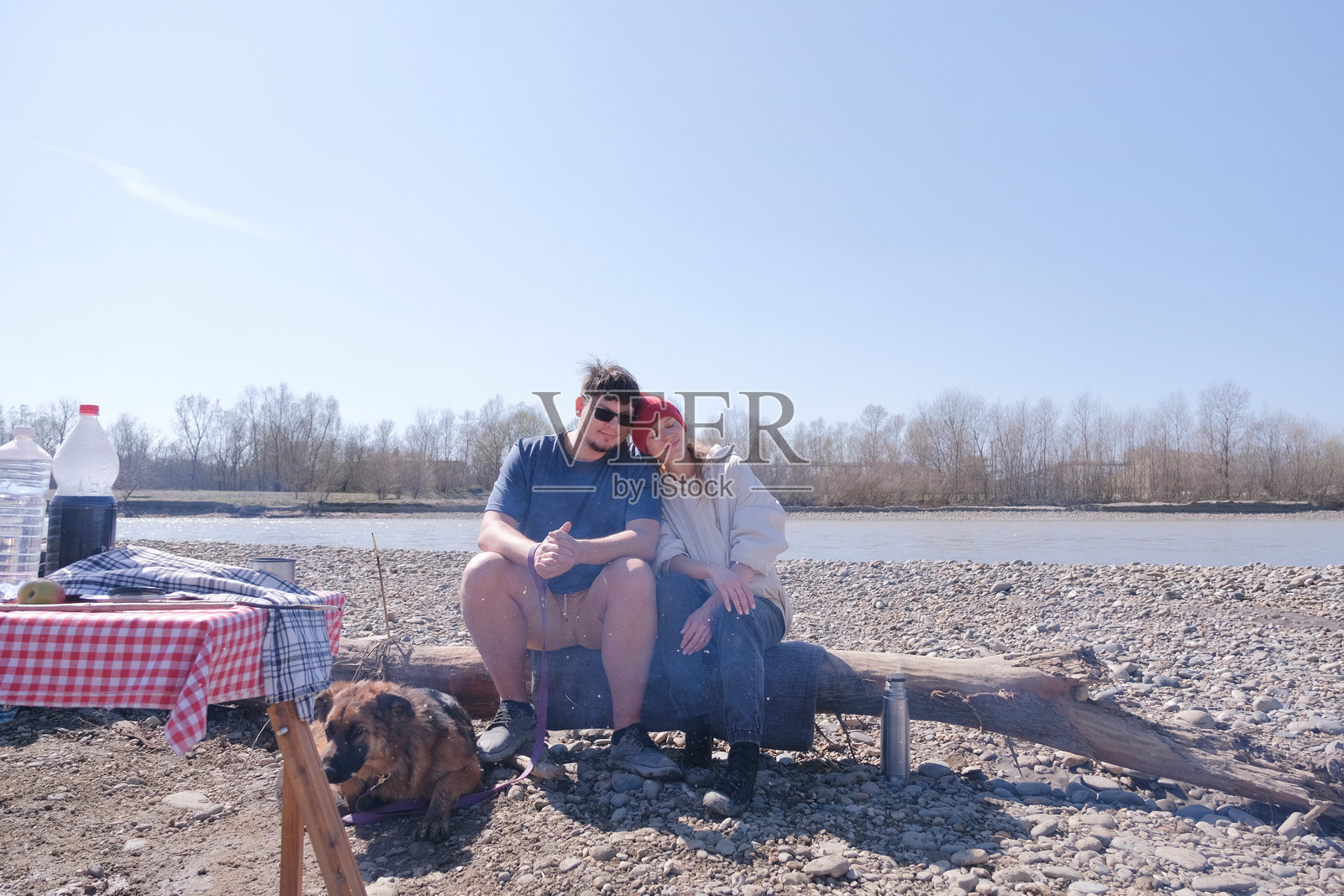 一家人在河边野餐，带着他们的狗。照片摄影图片