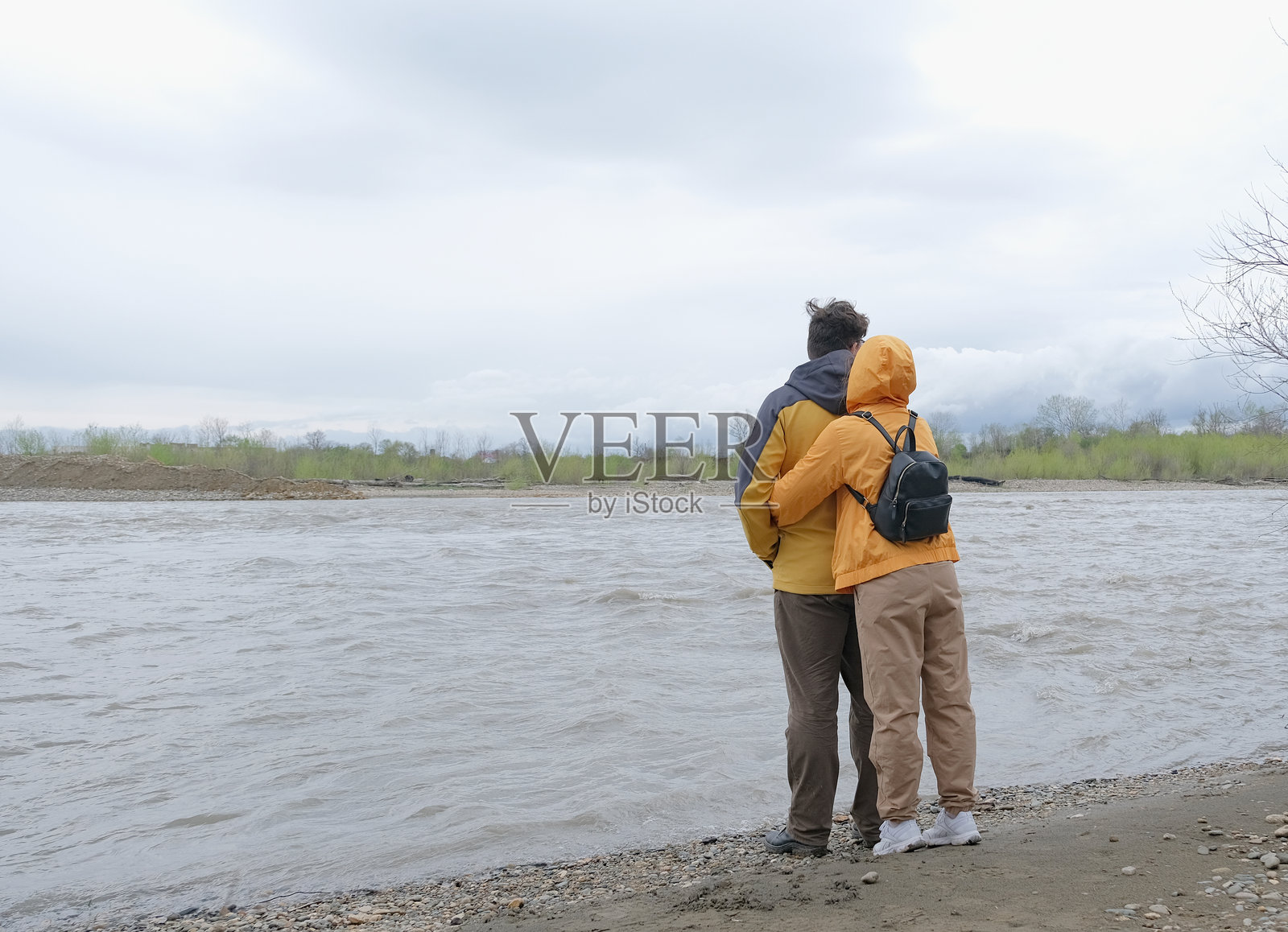 年轻情侣在河边拥抱，享受美丽的自然风光照片摄影图片