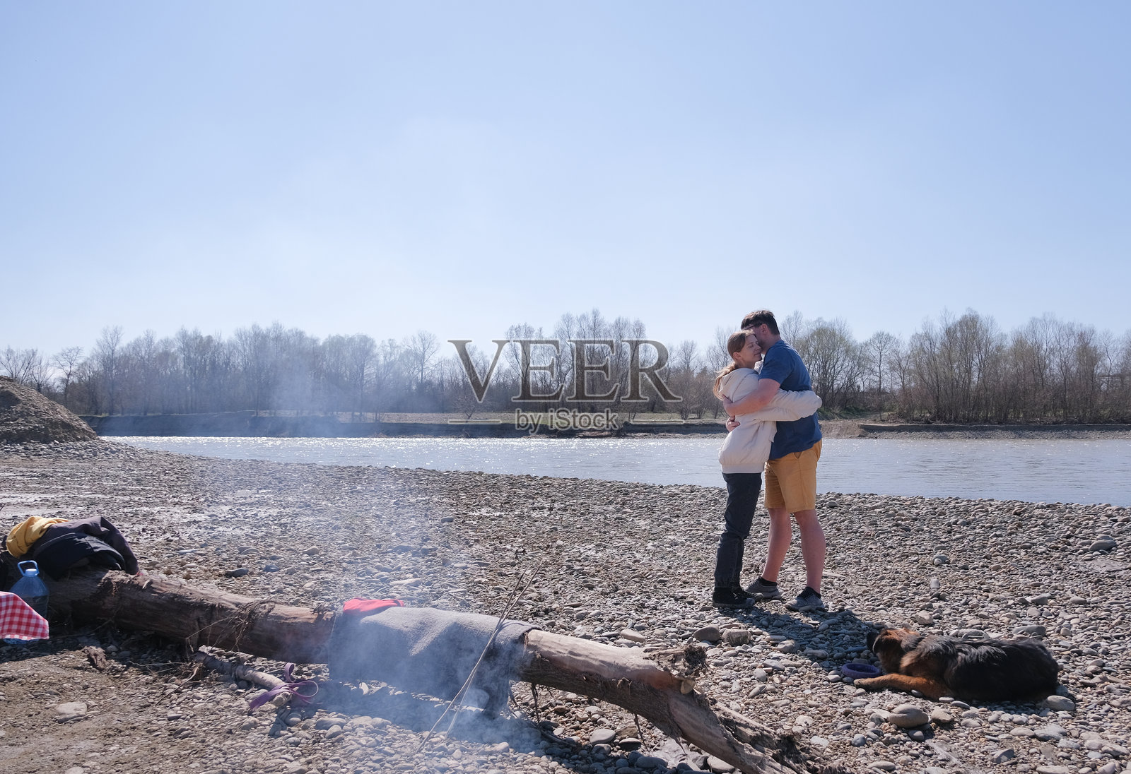 一家人在河边野餐，和他们的狗一起拥抱。照片摄影图片
