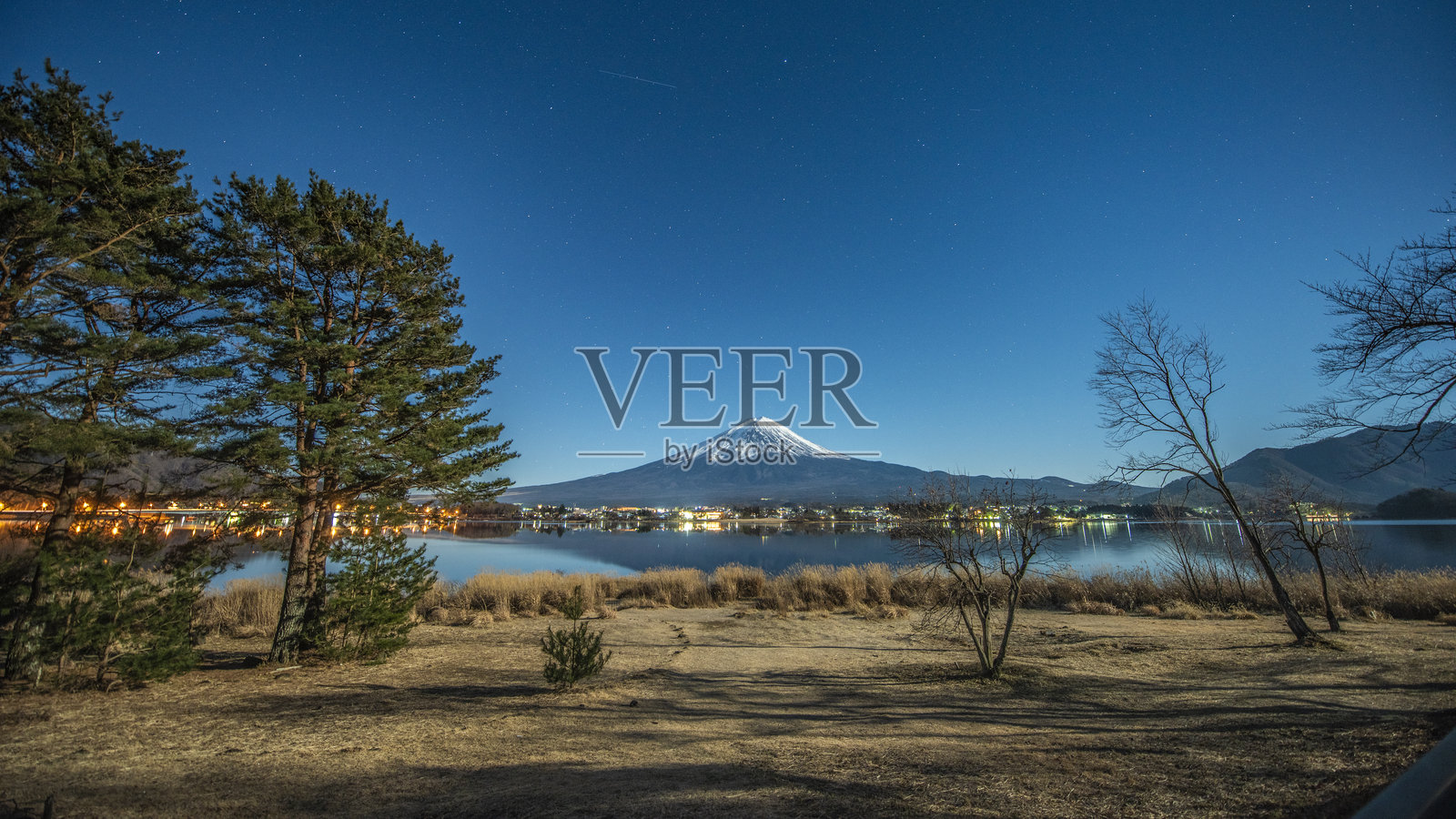 星空下的富士山，树木和湖边草地环绕着它照片摄影图片