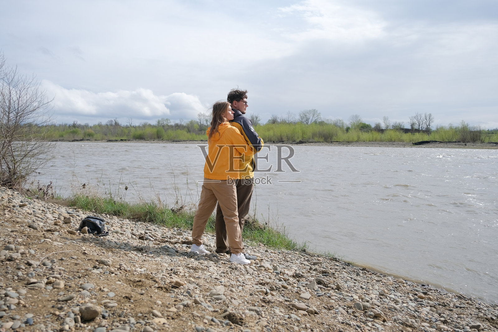 年轻情侣在河边拥抱，享受美丽的自然风光照片摄影图片
