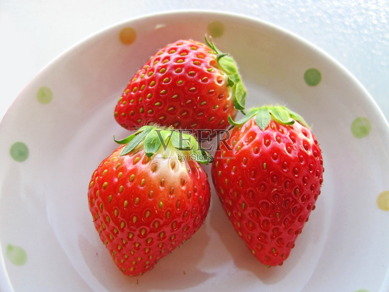 多颗丰硕的草莓放在白色盘子上照片摄影图片