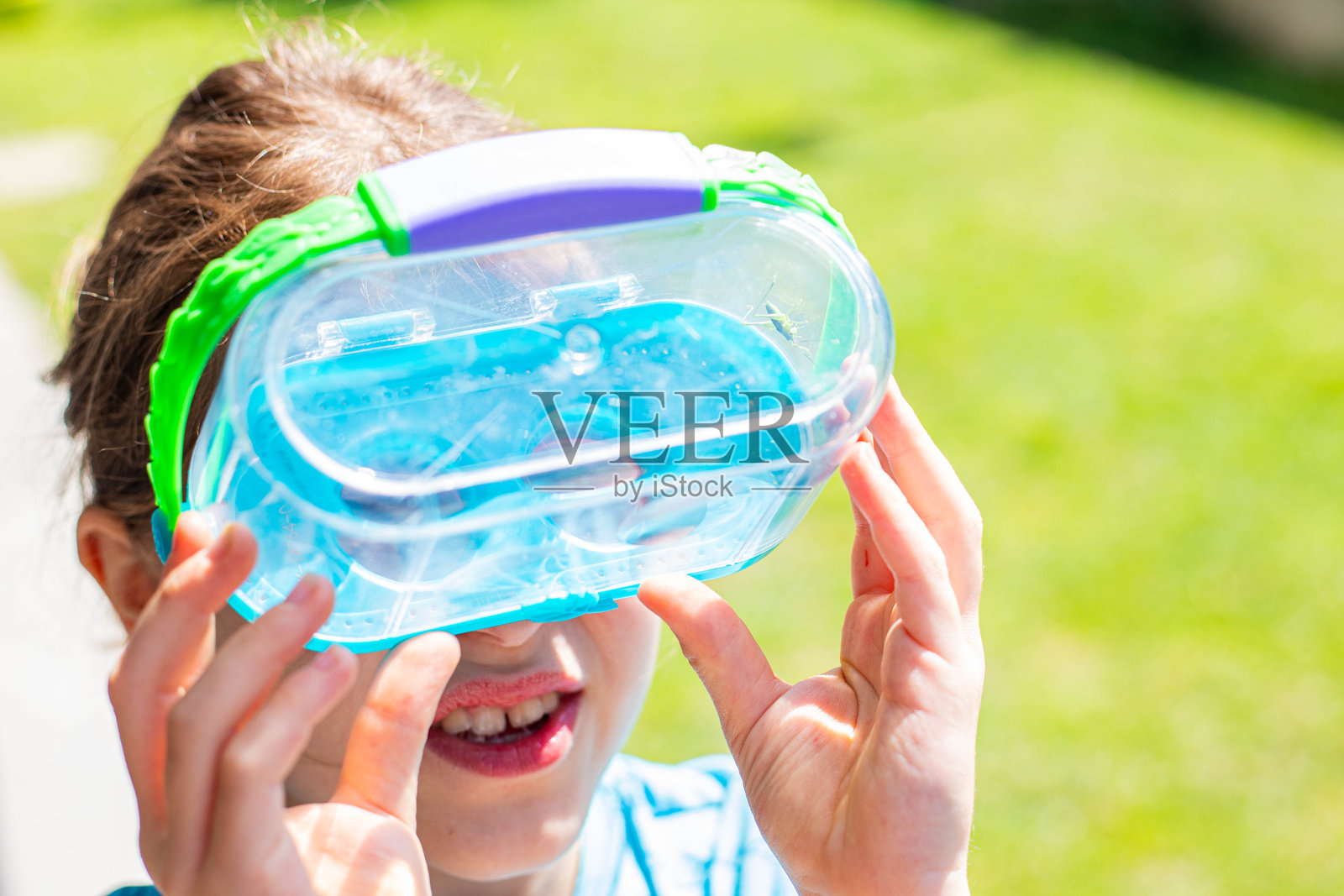 小女孩在昆虫放大盒中观察虫子。照片摄影图片