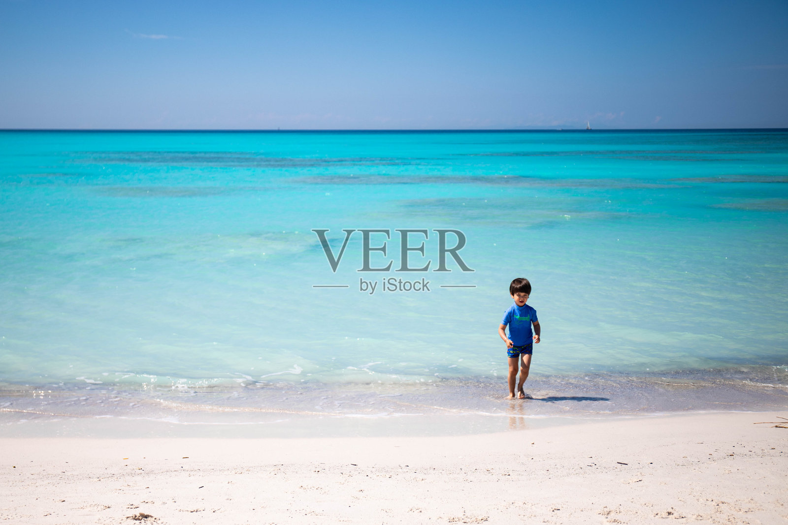 小男孩在托斯卡纳罗西尼亚诺·索尔瓦伊的白色海滩上欣赏令人难以置信的色彩。照片摄影图片