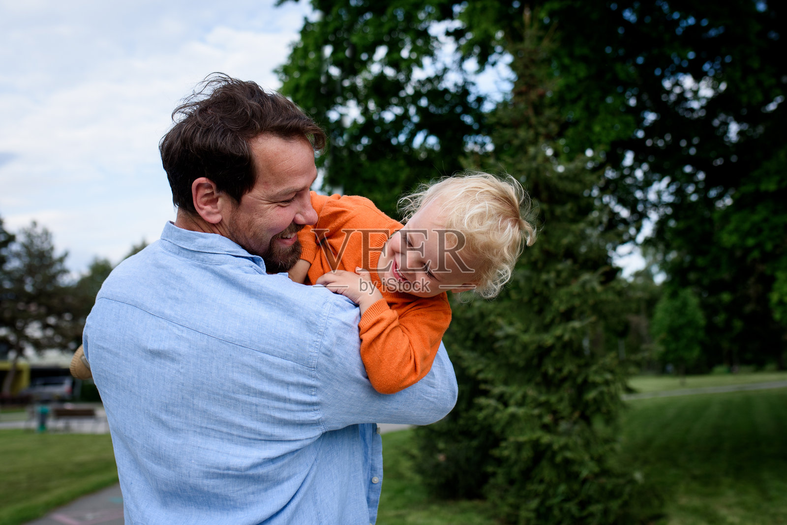 父亲在公园里与幼儿儿子玩耍照片摄影图片