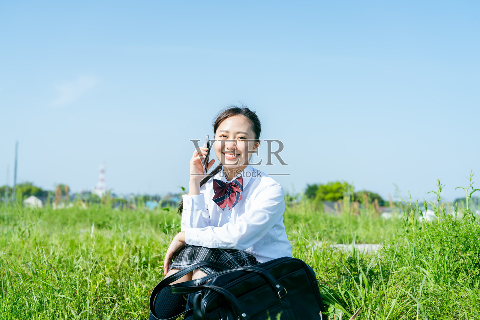 高中女孩在蓝天之下拿着智能手机照片摄影图片