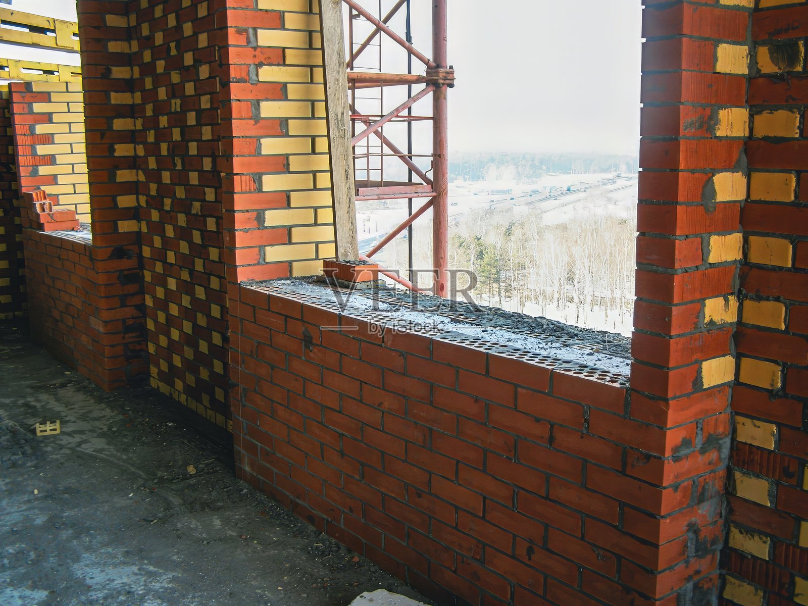 一面砖墙的室内建筑视图，外面可见冬季风景。照片摄影图片