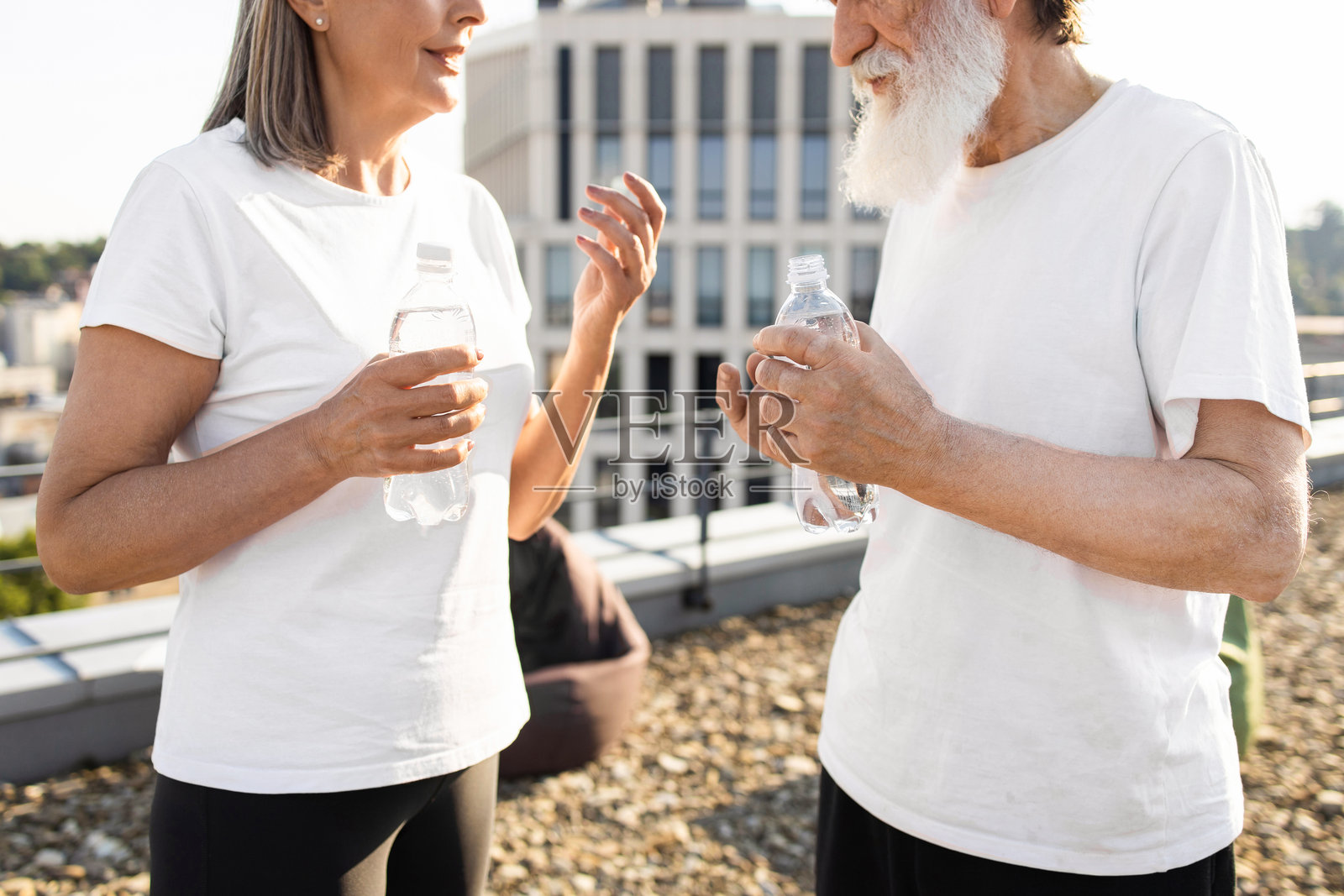 一对老年夫妇在户外享受清爽的休息时光，手里拿着瓶装水照片摄影图片