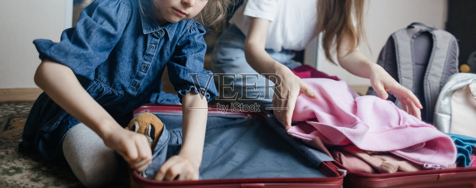 疲惫的母亲与6岁女儿一起打包旅行行李。旅行概念。旅行包的特写以及旅客疲惫的面孔。照片摄影图片