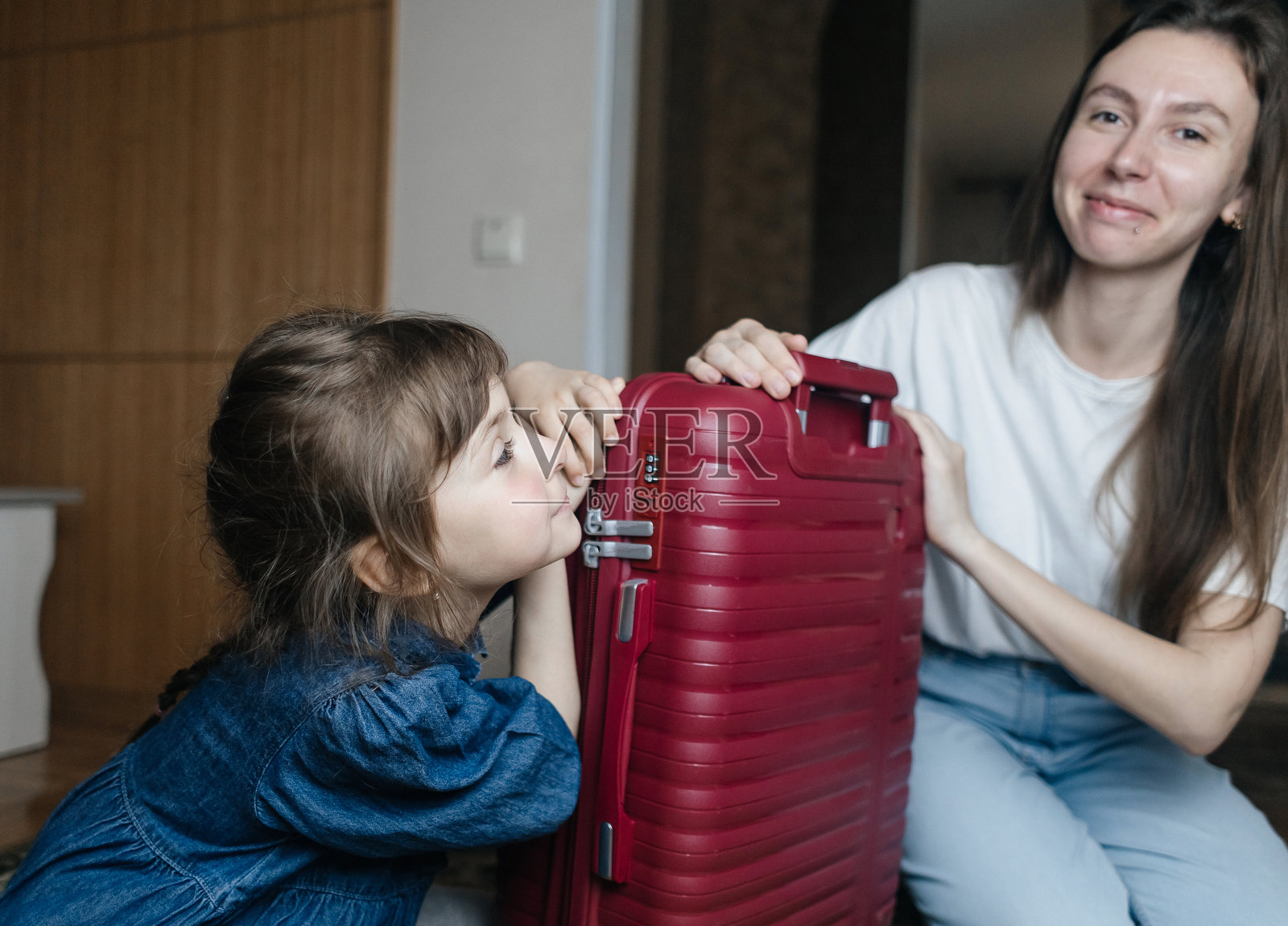 疲惫的母亲与6岁女儿一起打包旅行行李。旅行概念。旅行包的特写以及旅客疲惫的面孔。照片摄影图片