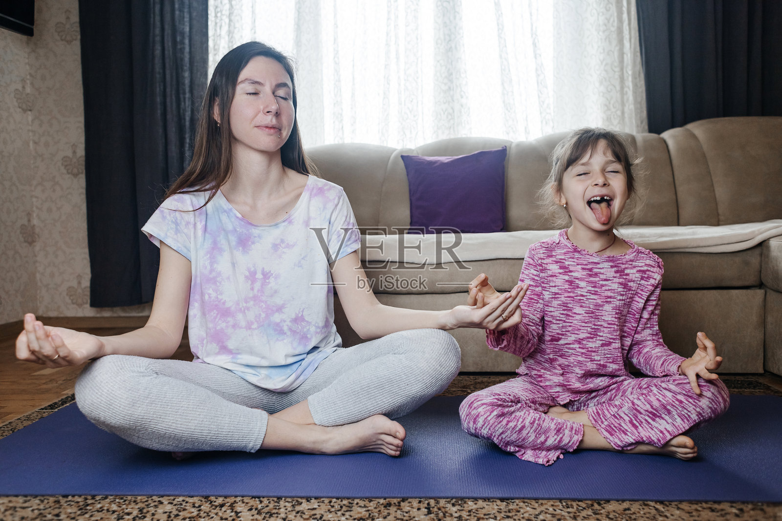 母亲和女儿在家做瑜伽和冥想。一起在家锻炼。快乐而活跃的家庭时光。照片摄影图片