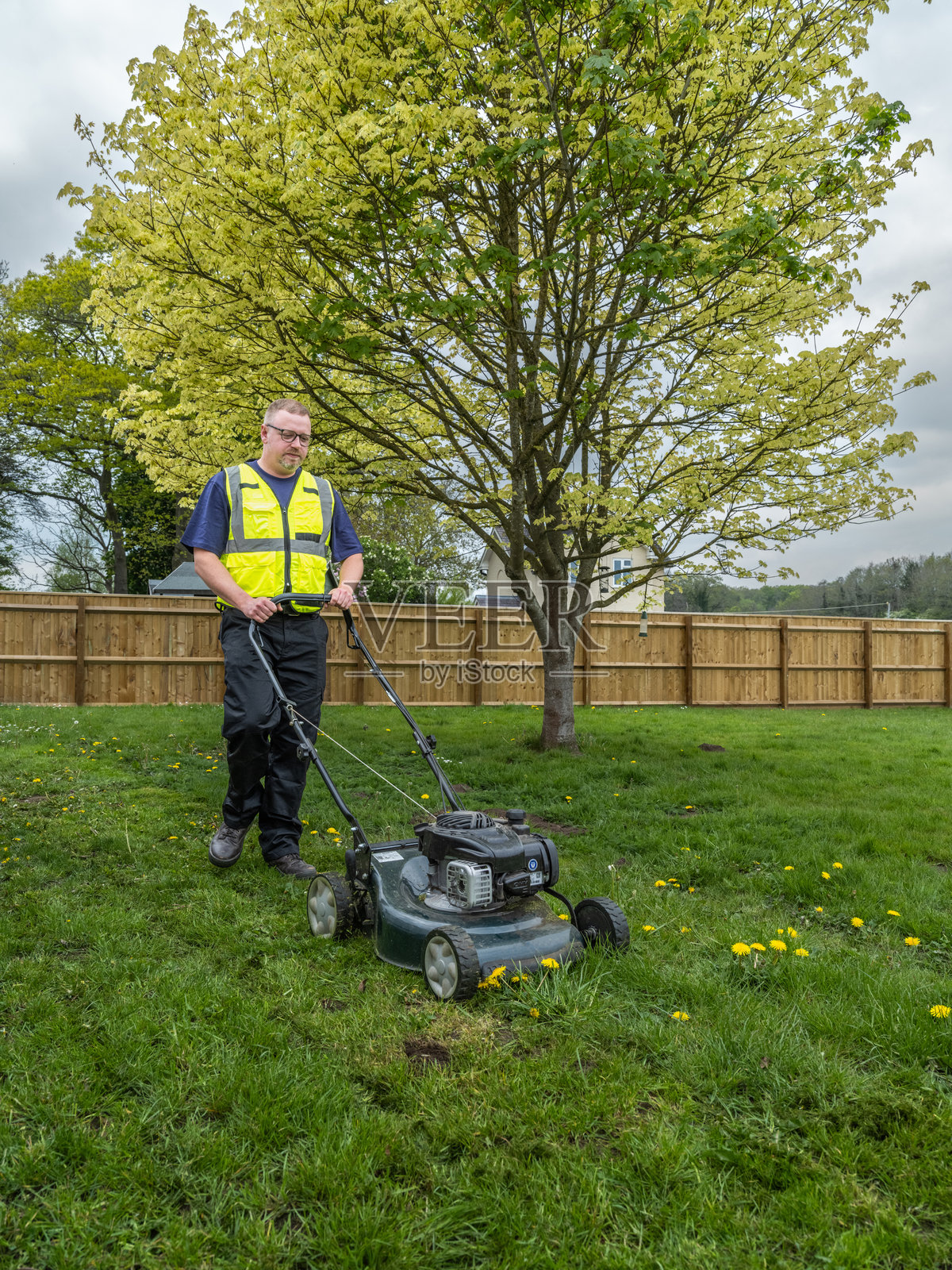 阴天里修剪草坪的男人照片摄影图片
