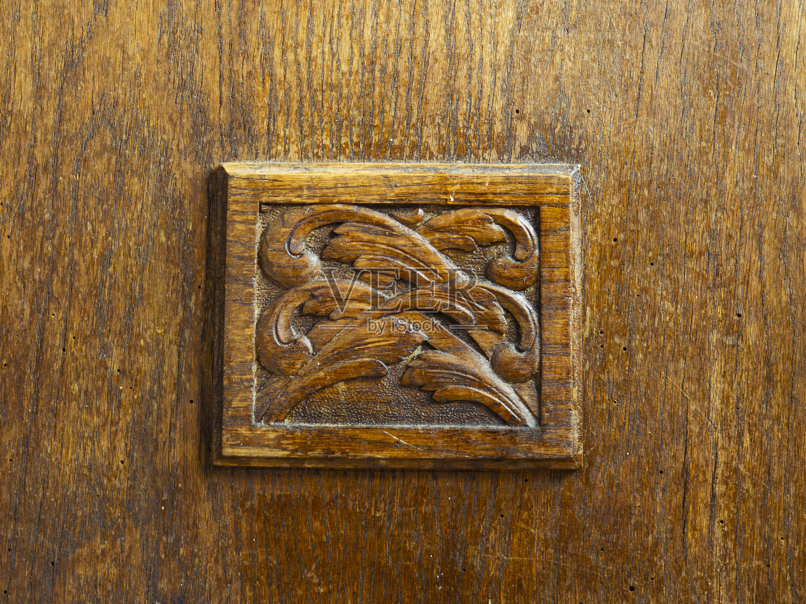 精美的木雕展示了细致的叶子图案，突显了工艺和艺术性，位于一件复古家具上照片摄影图片