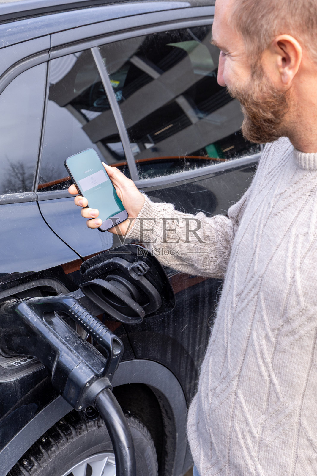 男子使用智能手机支付电动车充电费用照片摄影图片