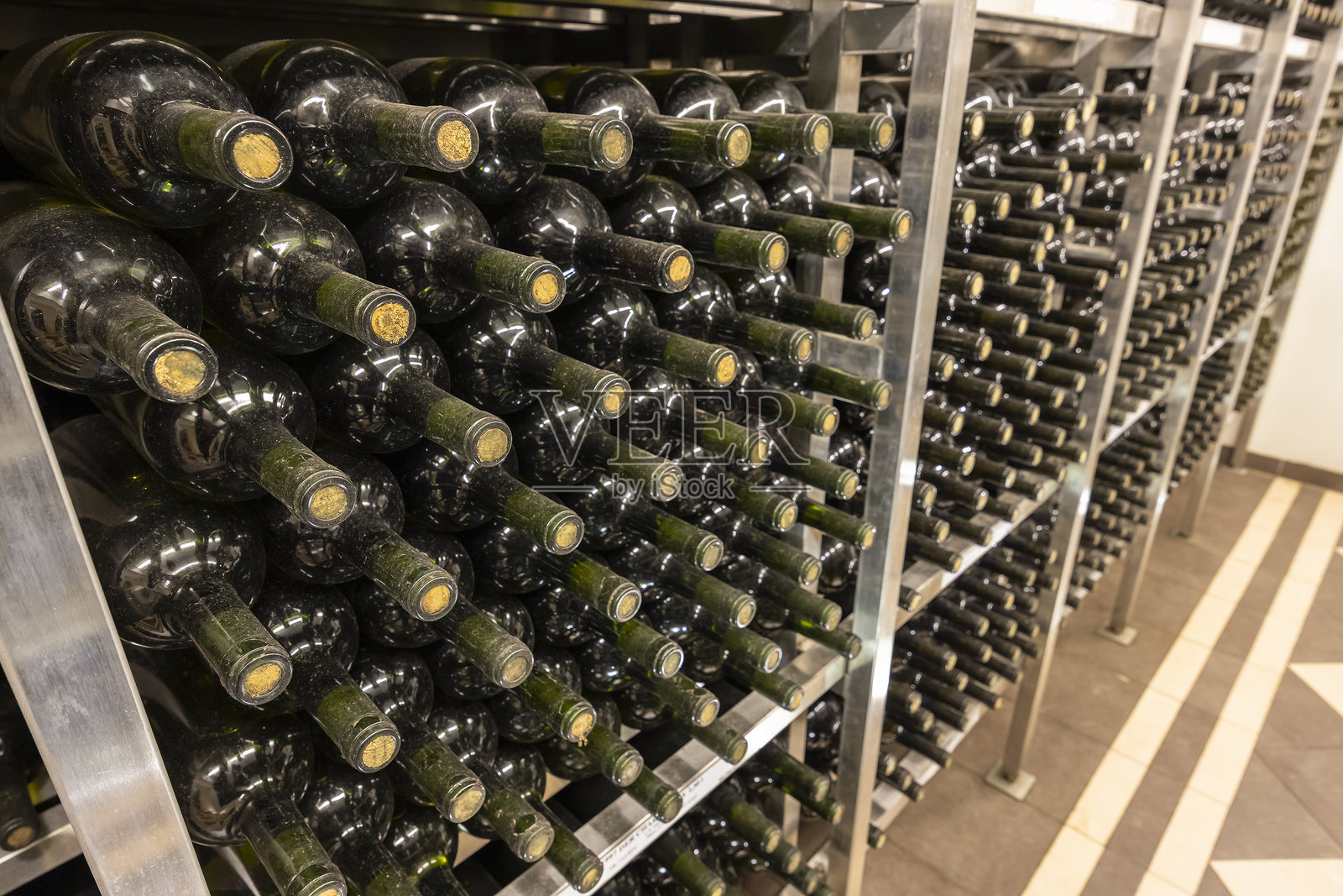 酒瓶在瓷砖地面的酒窖金属架上陈放。照片摄影图片