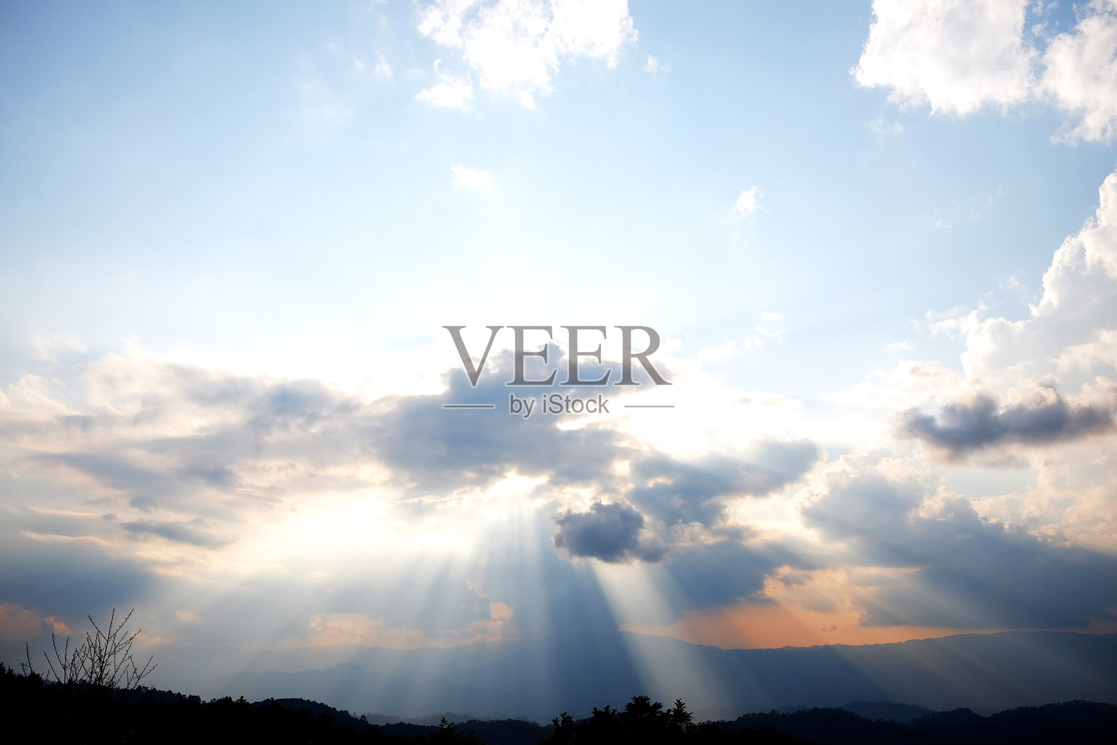 戏剧性的天空，阳光透过山脉照射下来照片摄影图片